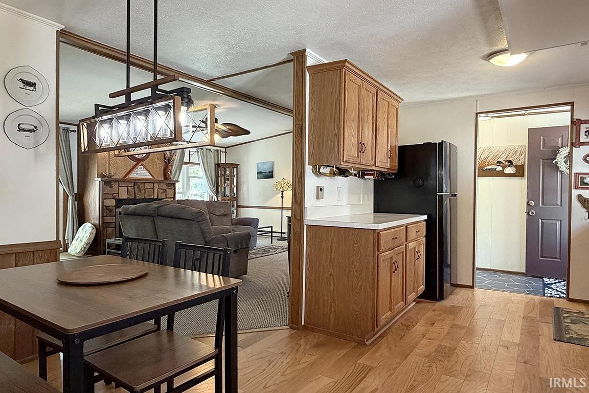 Kitchen featuring wood-finish flooring, oak cabinetry, white countertops, and a black refrigerator