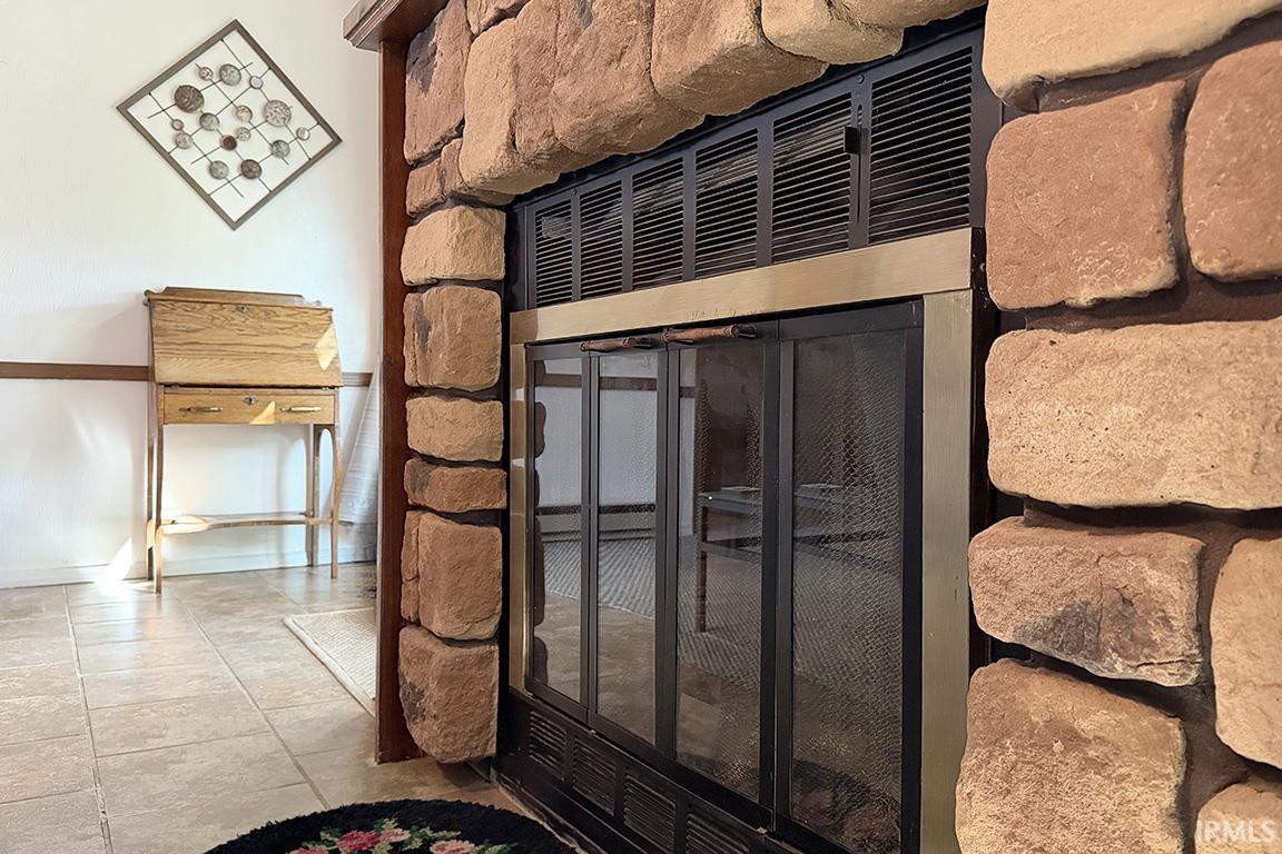 Stone fireplace featuring a metal fire screen and a stone hearth