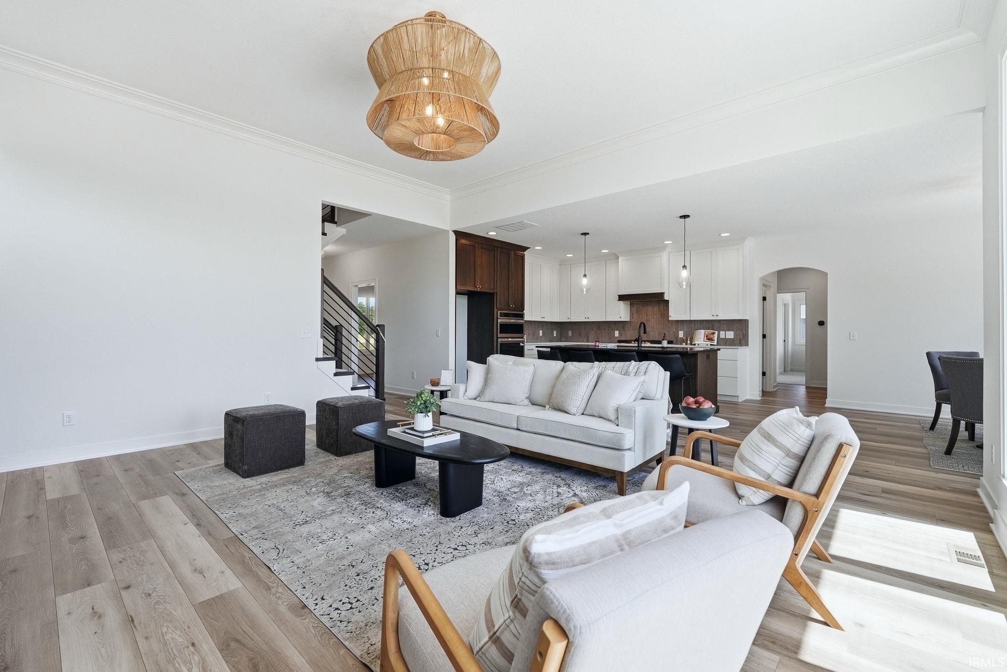 Spacious living area featuring light wood-finish flooring and crown molding