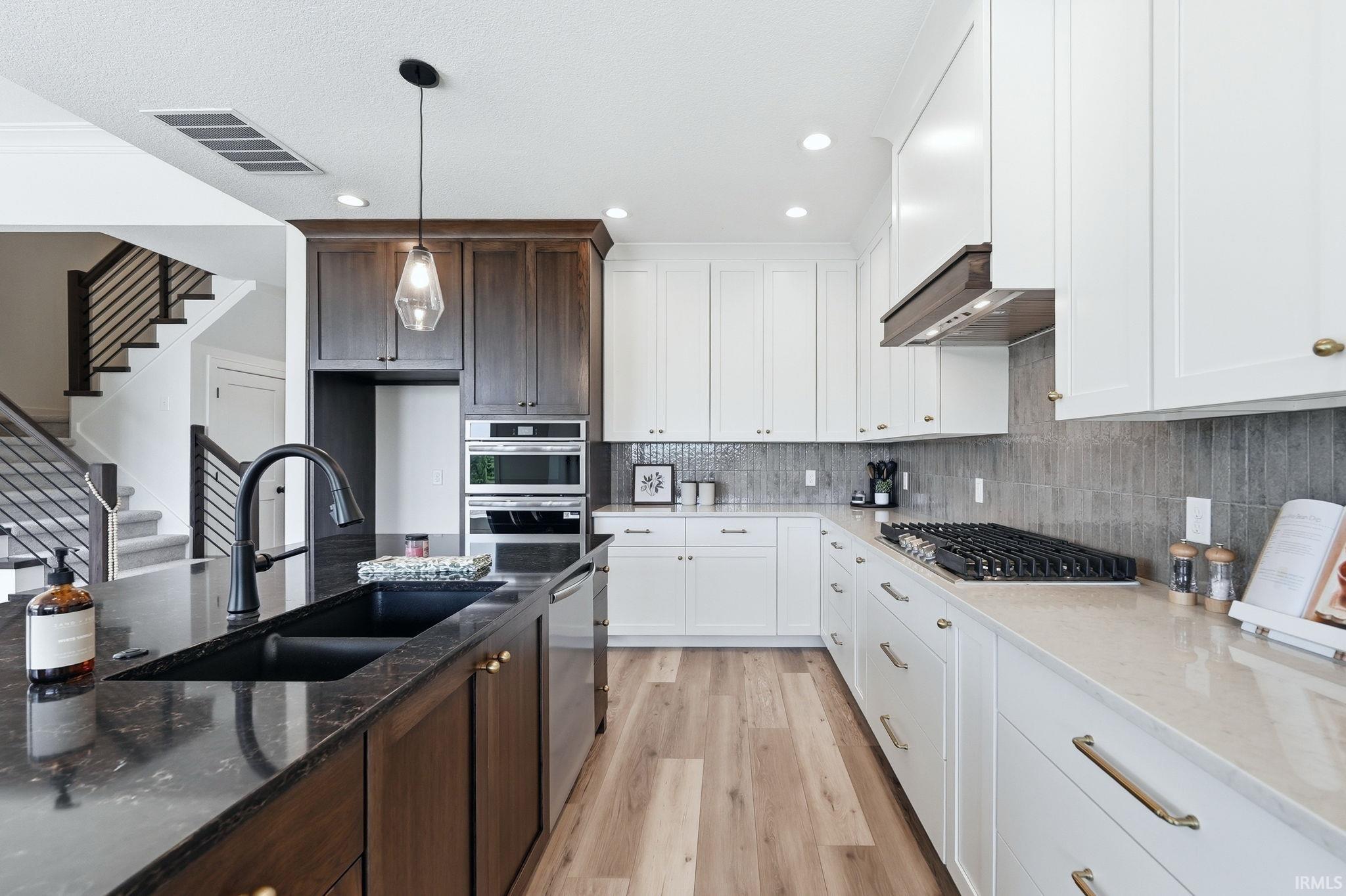 Gourmet kitchen featuring a central island with a dual basin sink, black fixture, and dark countertop