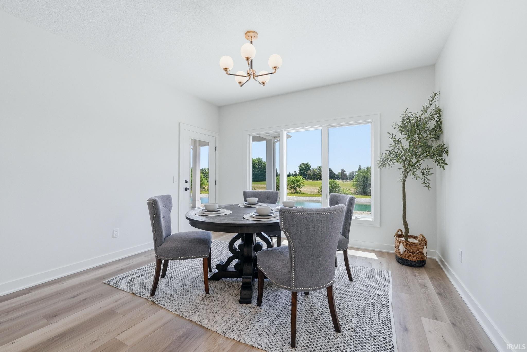 Dining space featuring a modern chandelier, large windows with exterior water views, a glass-paned exterior door, and wood-finish flooring