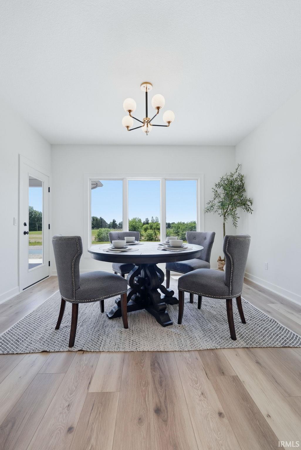 Dining area with wood-finish flooring, a contemporary chandelier, and large windows