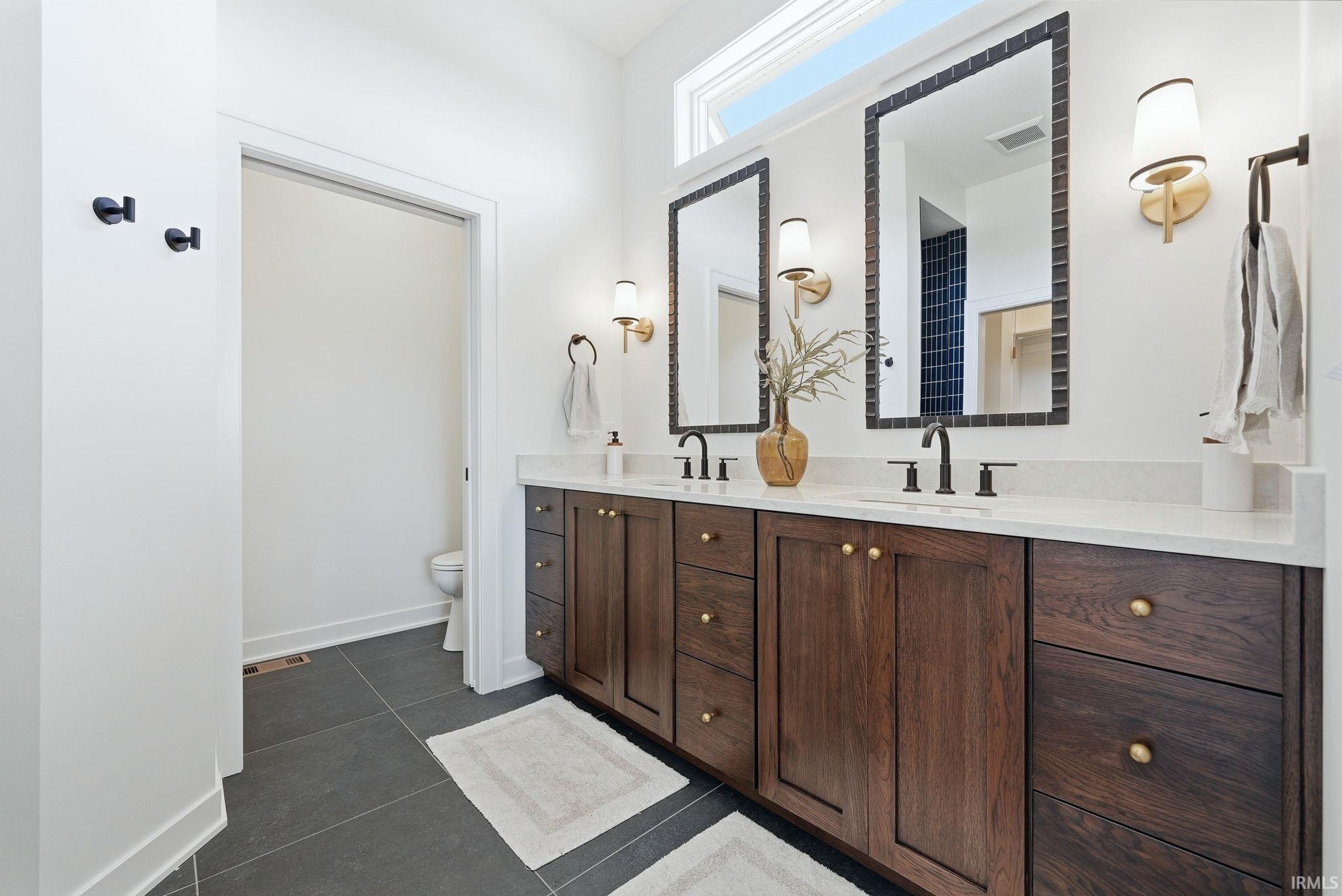 Double vanity featuring wood cabinetry, white countertops, and matte black fixtures