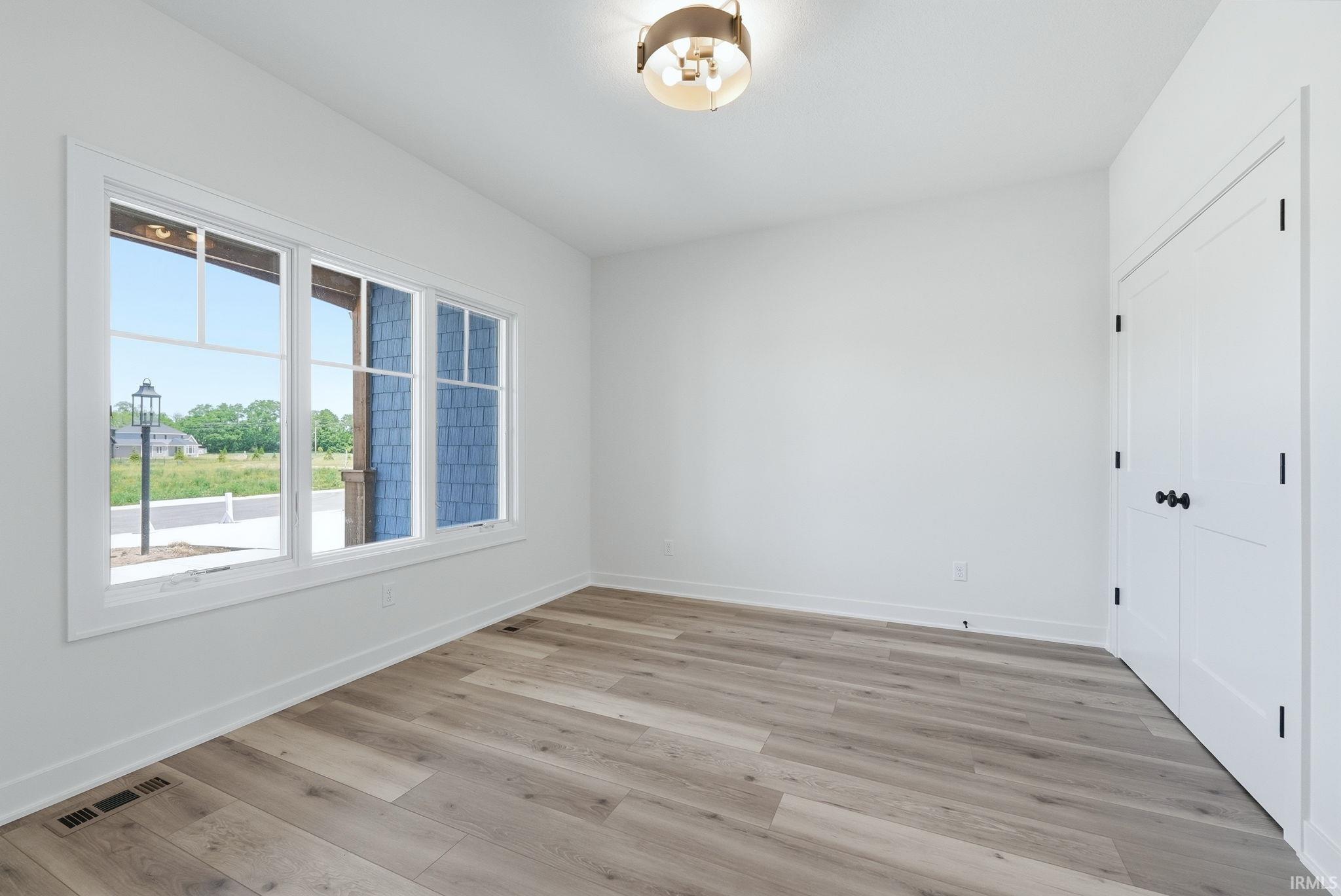 Bright interior space featuring wood-finish flooring, white trim, and a contemporary flush-mount light fixture