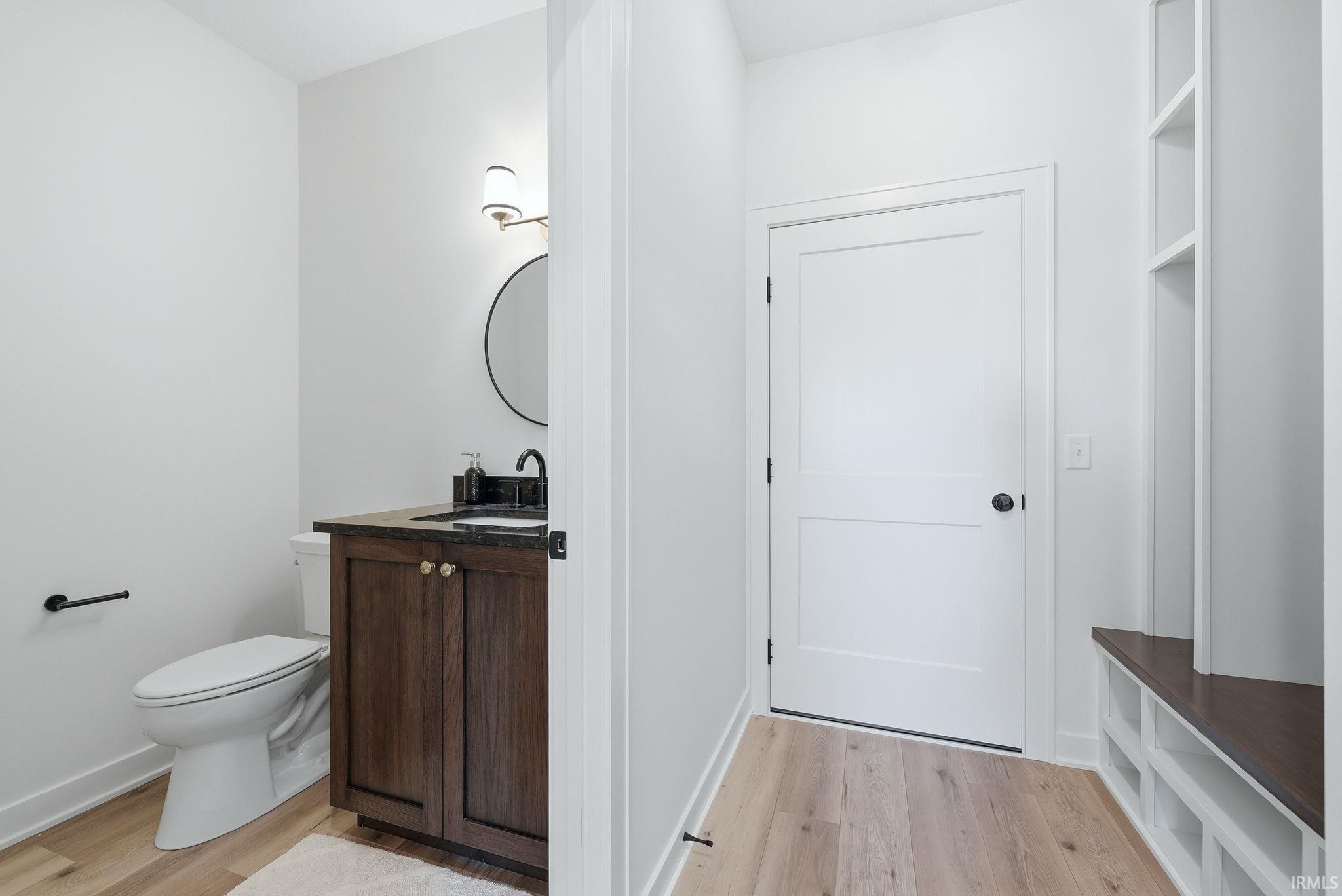 Powder room featuring a dark wood vanity with a black sink, round mirror, and wall-mounted lighting