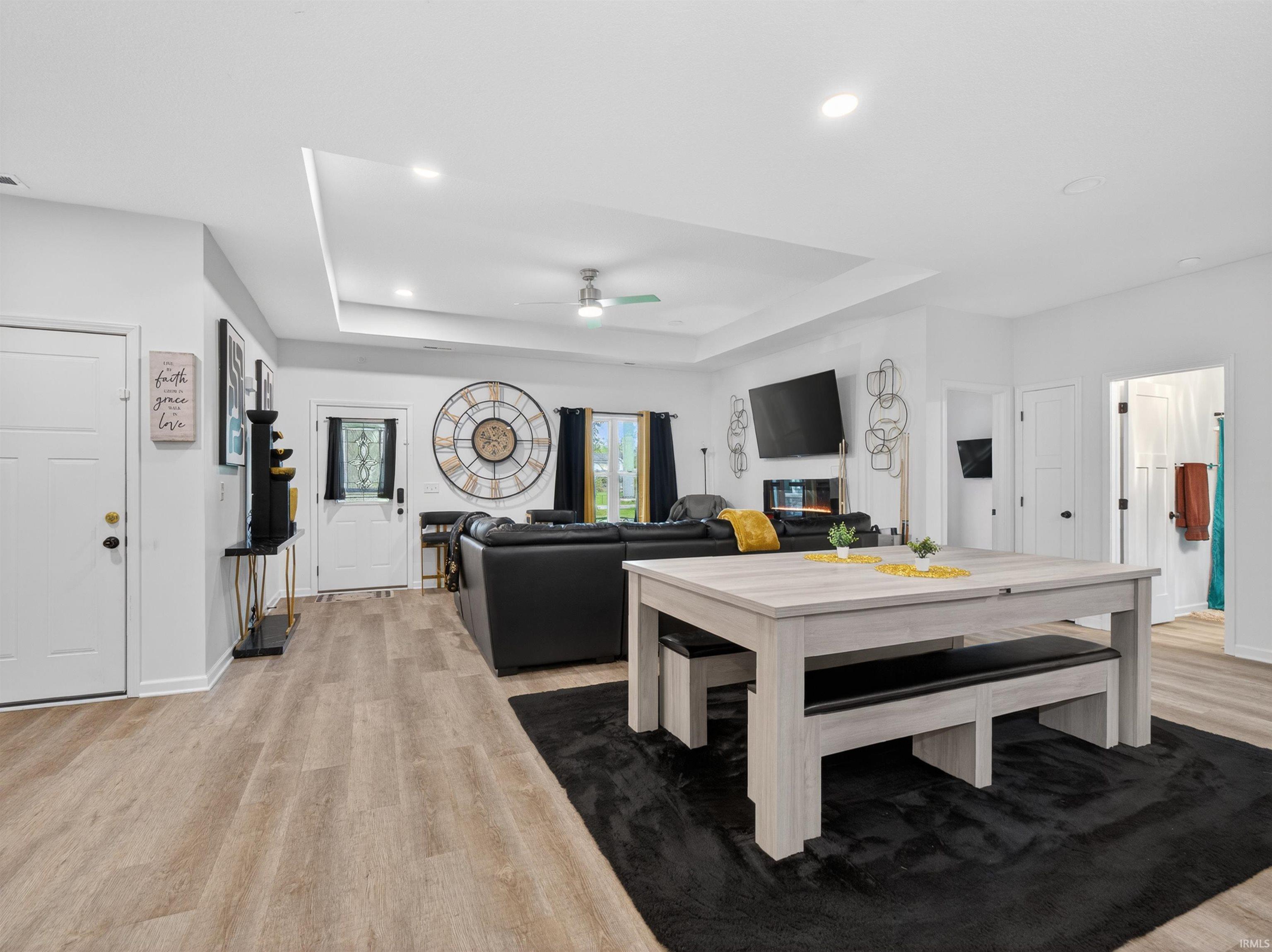 Spacious open-concept interior featuring light wood-finish flooring, recessed ceiling lighting, a contemporary recessed fireplace, and white paneled doors