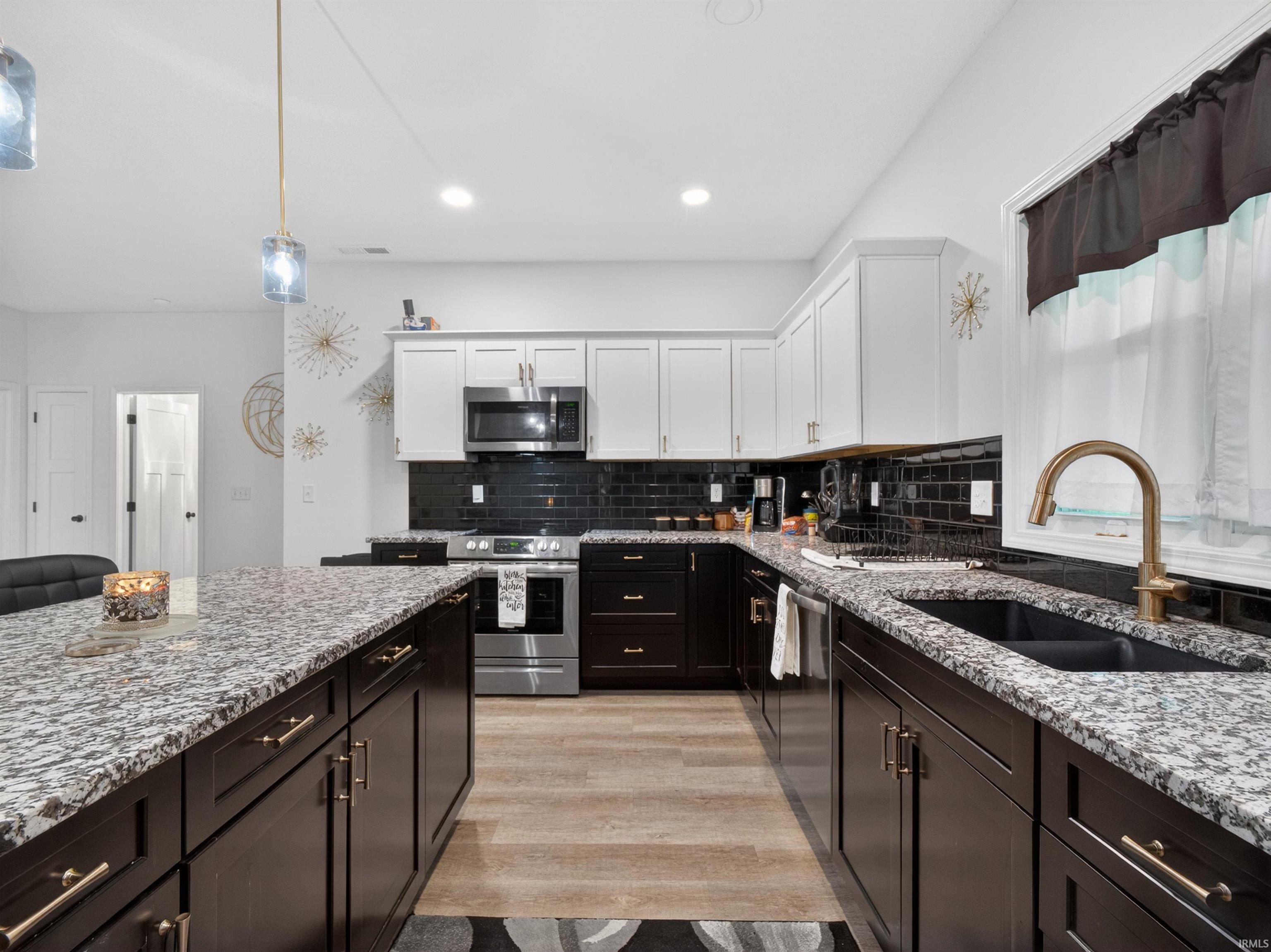 Spacious kitchen featuring dark lower cabinetry, light upper cabinetry, and a dark tile backsplash