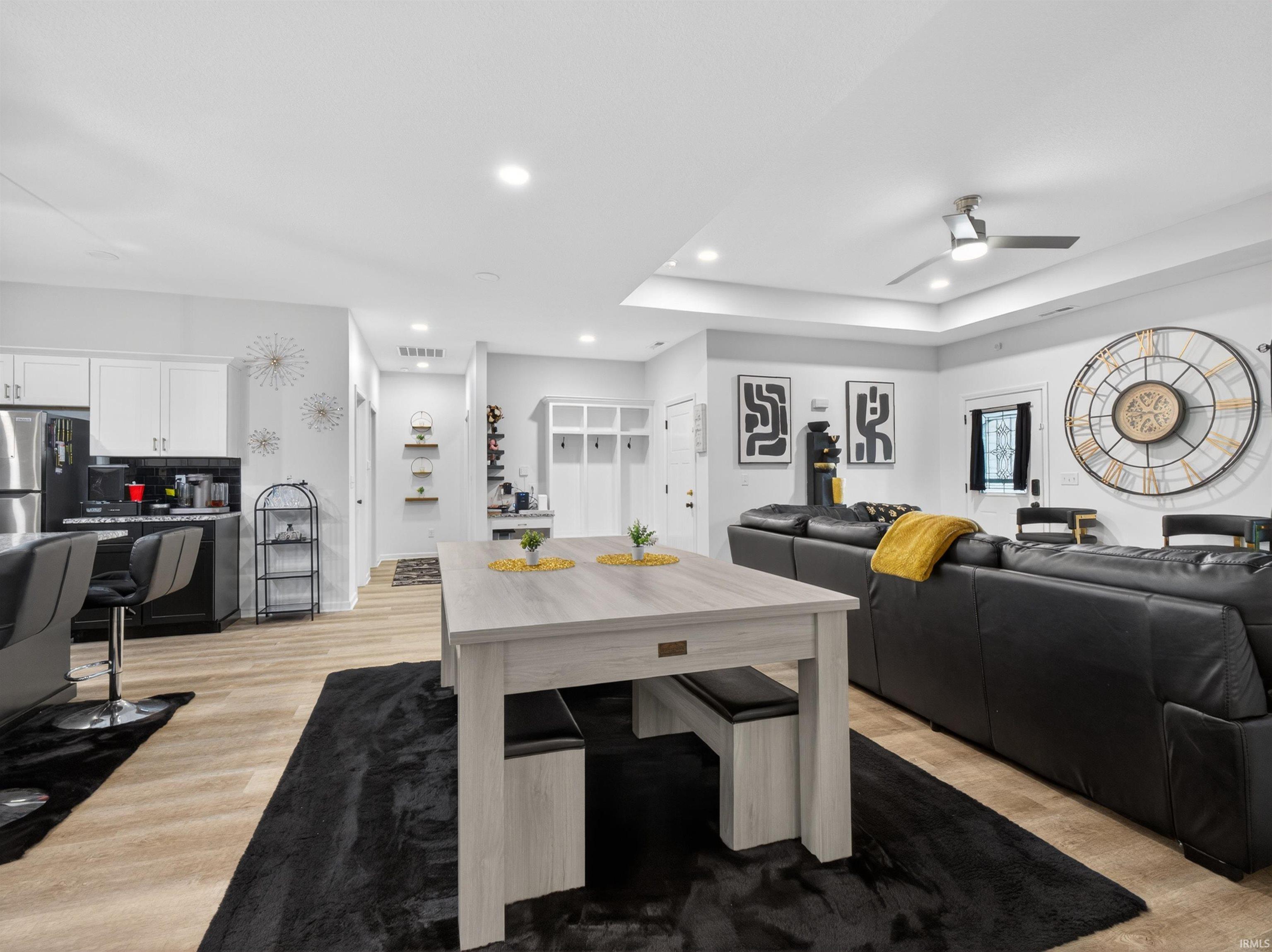 Open-concept living area featuring light wood-finish flooring, recessed lighting, a ceiling fan, and a large central table