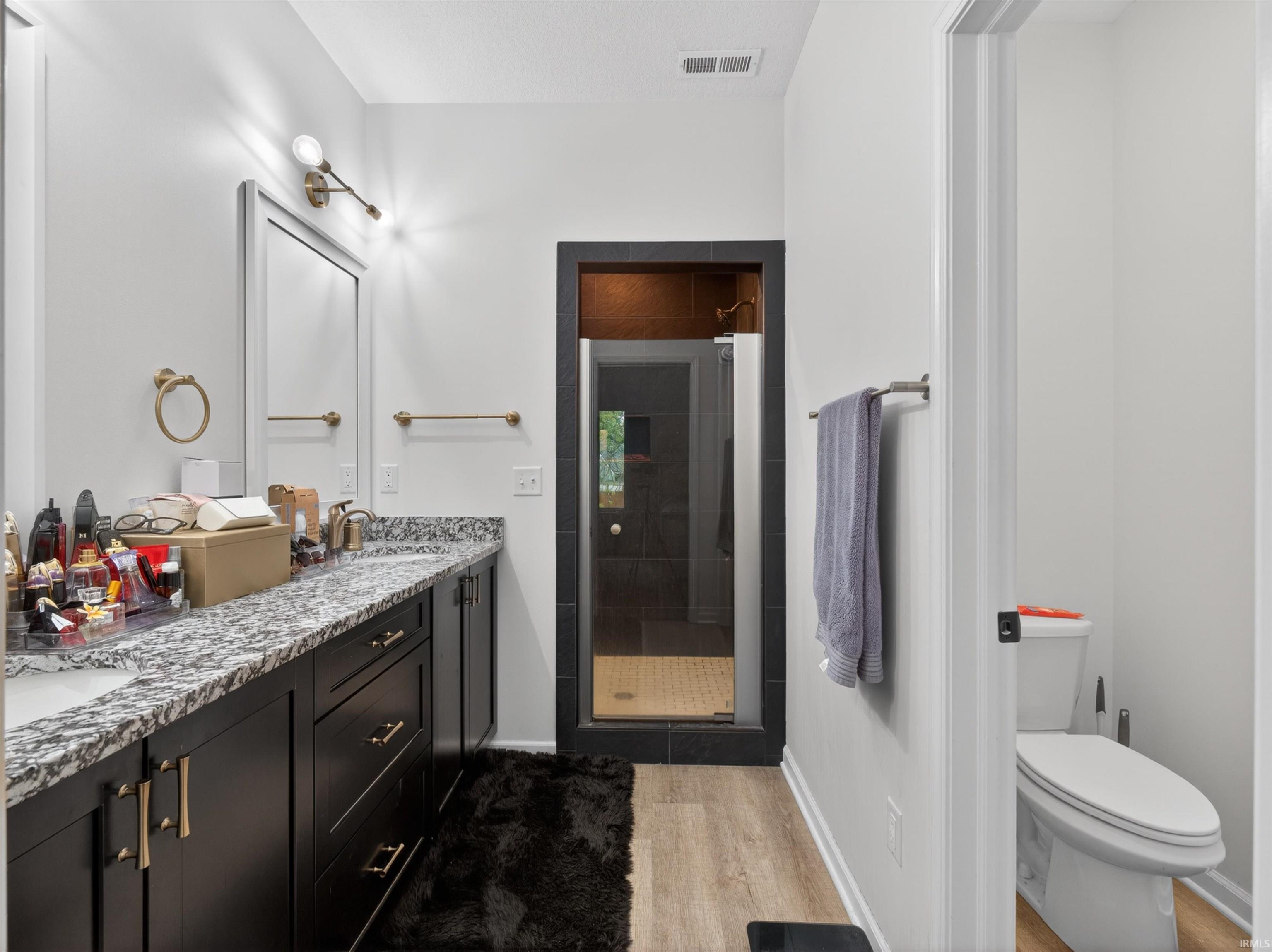 Bathroom featuring a double vanity with stone countertops, dark cabinetry, and dual sinks