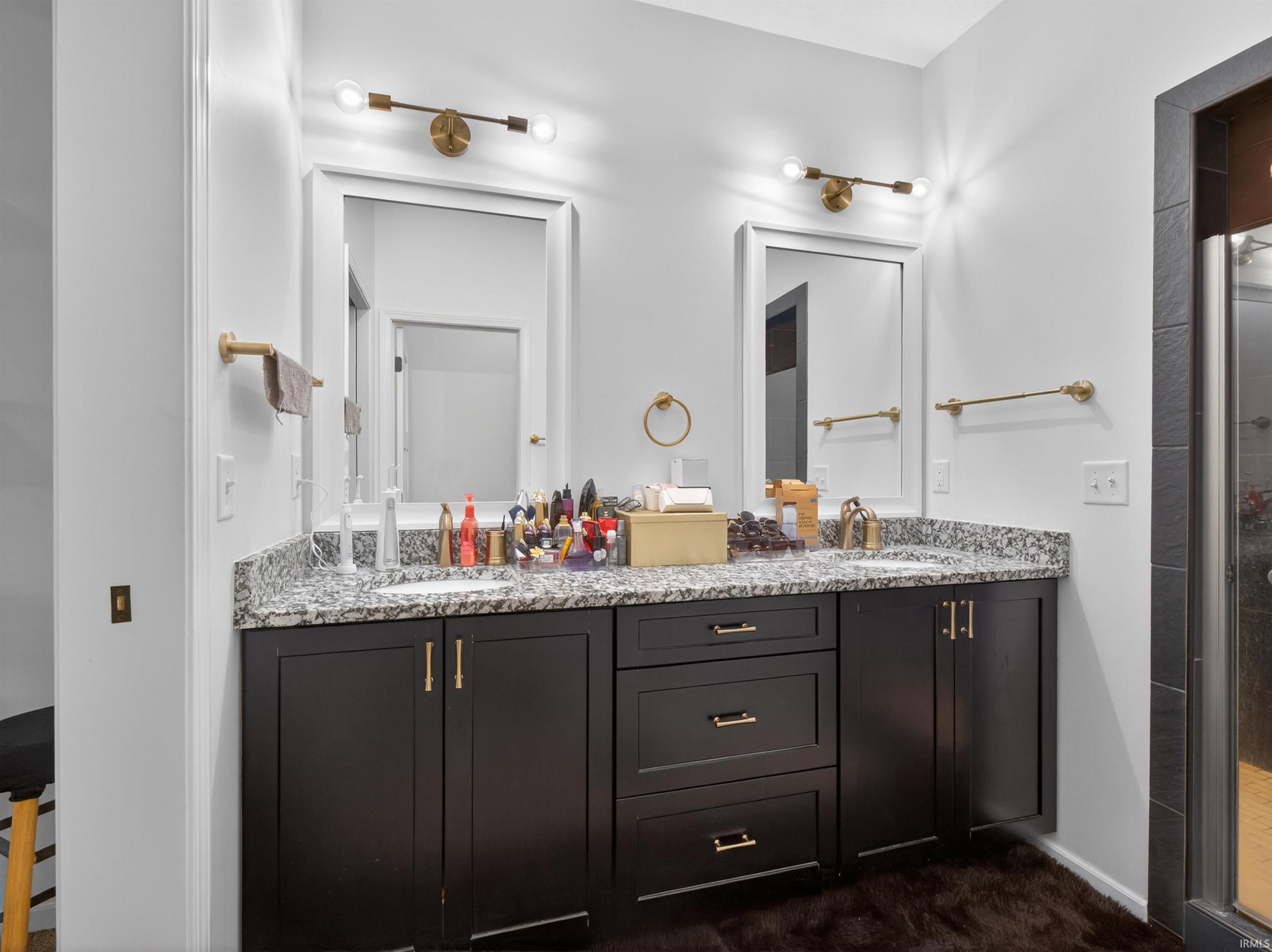 Double vanity with dark wood cabinetry, light speckled countertop, and rectangular undermount sinks