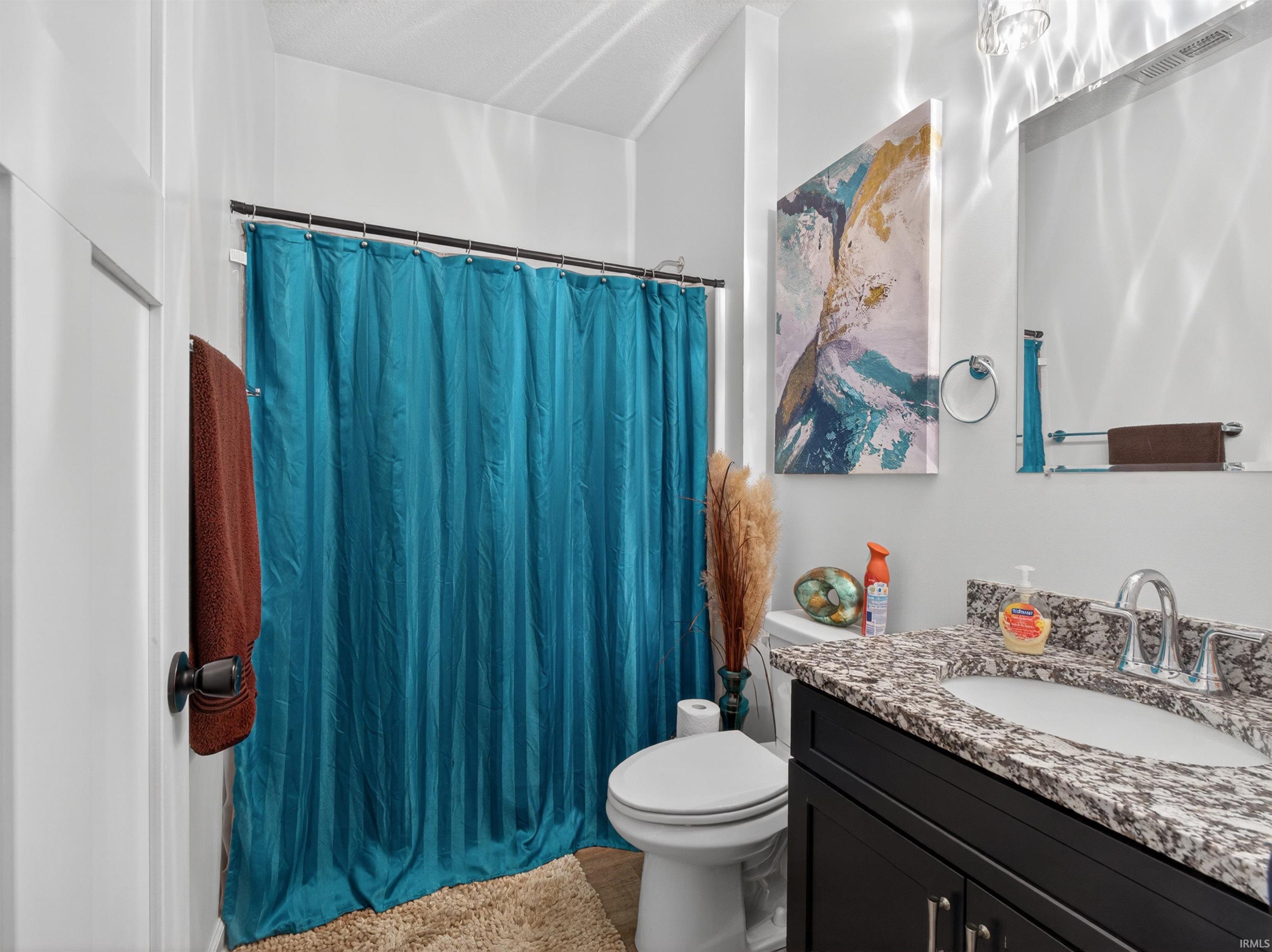 Bathroom featuring a dark wood vanity with a light granite countertop, undermount sink, and chrome faucet