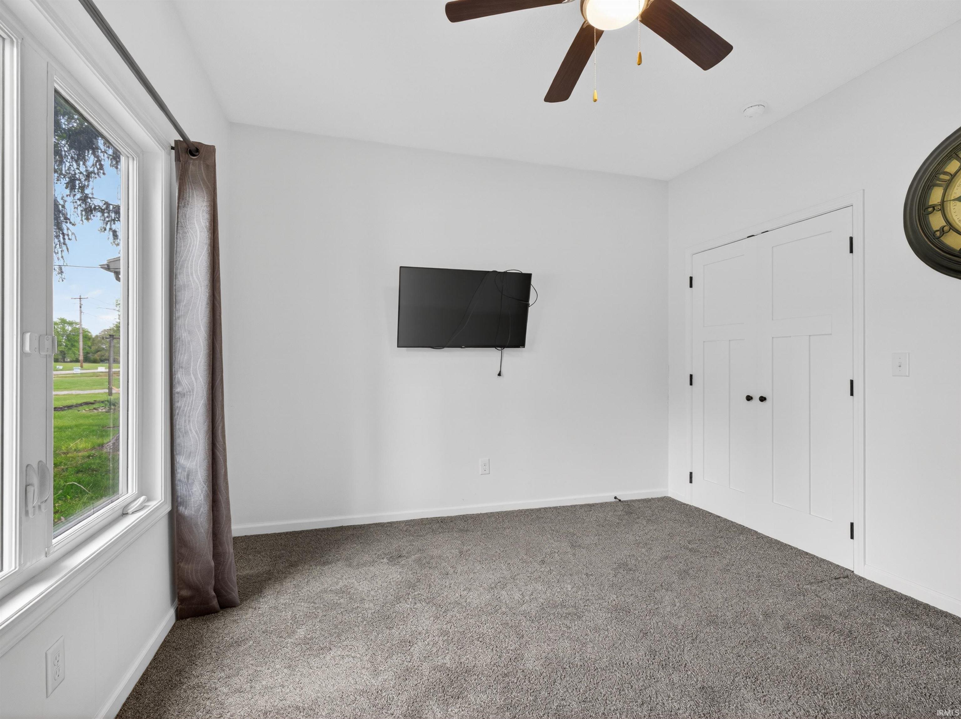 Spacious room featuring light gray carpeting and white walls