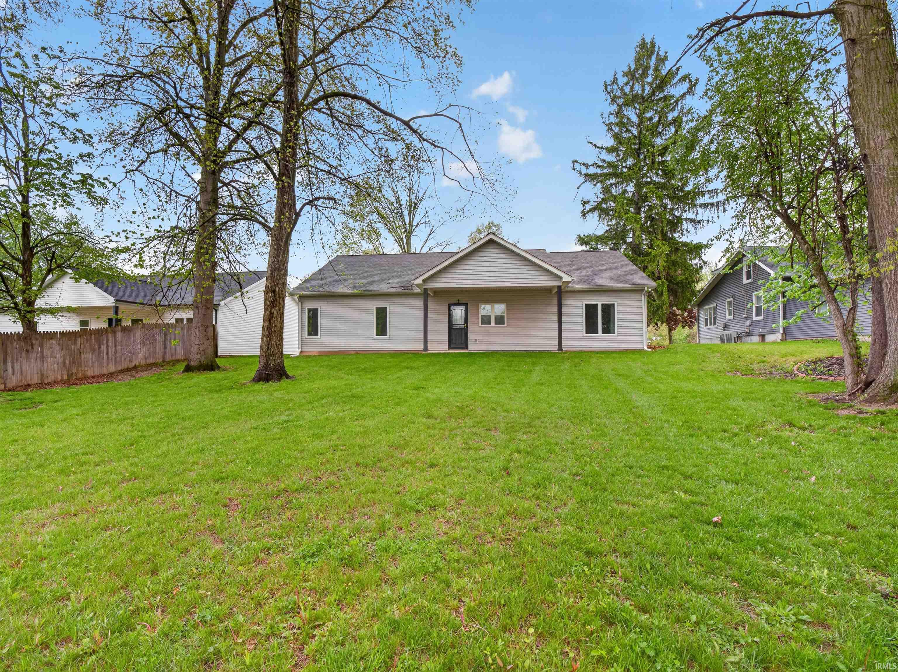 Expansive green lawn with mature trees and a wood fence