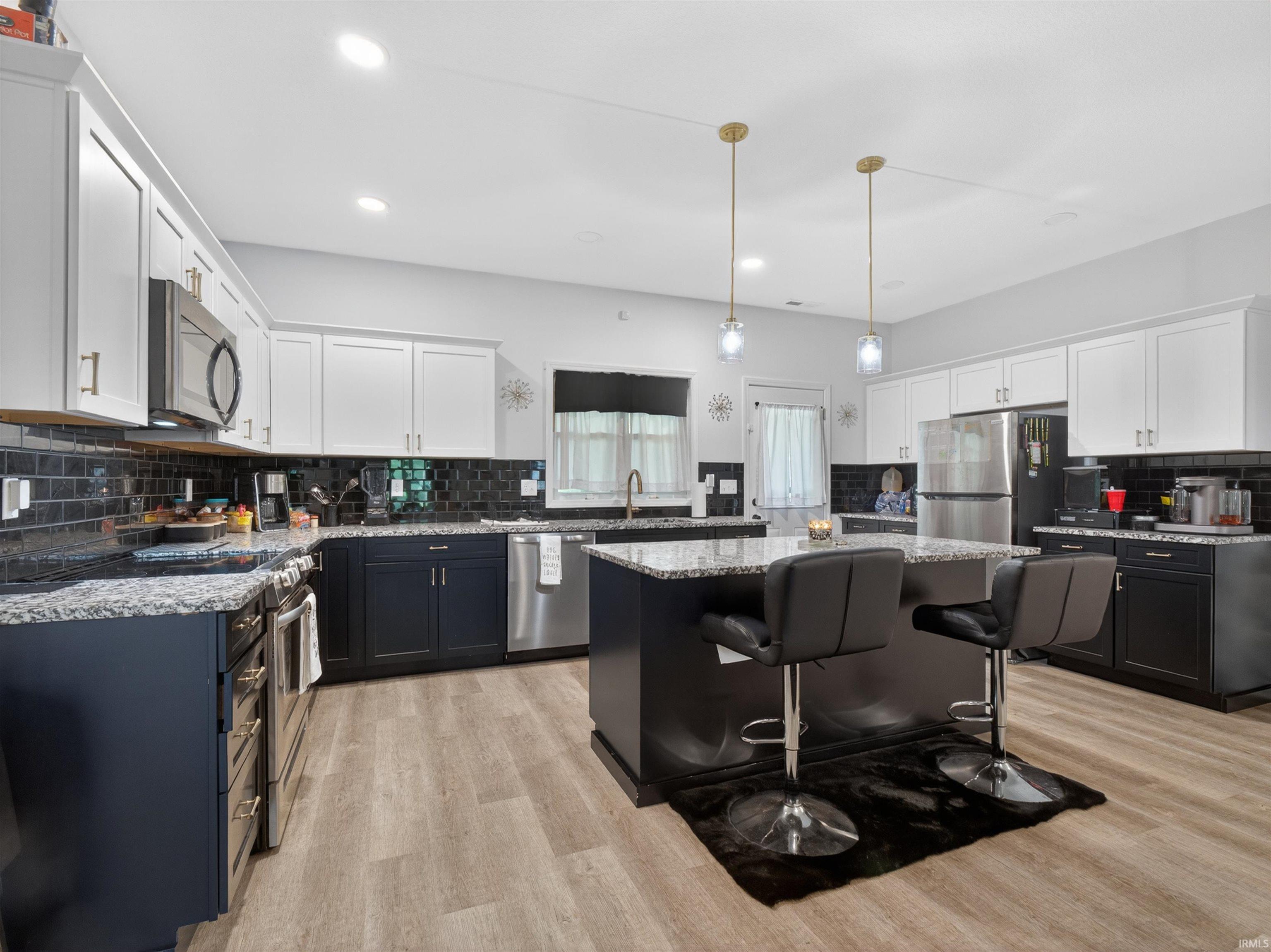 Kitchen featuring two-tone cabinetry, stainless steel appliances, granite countertops, and a subway tile backsplash