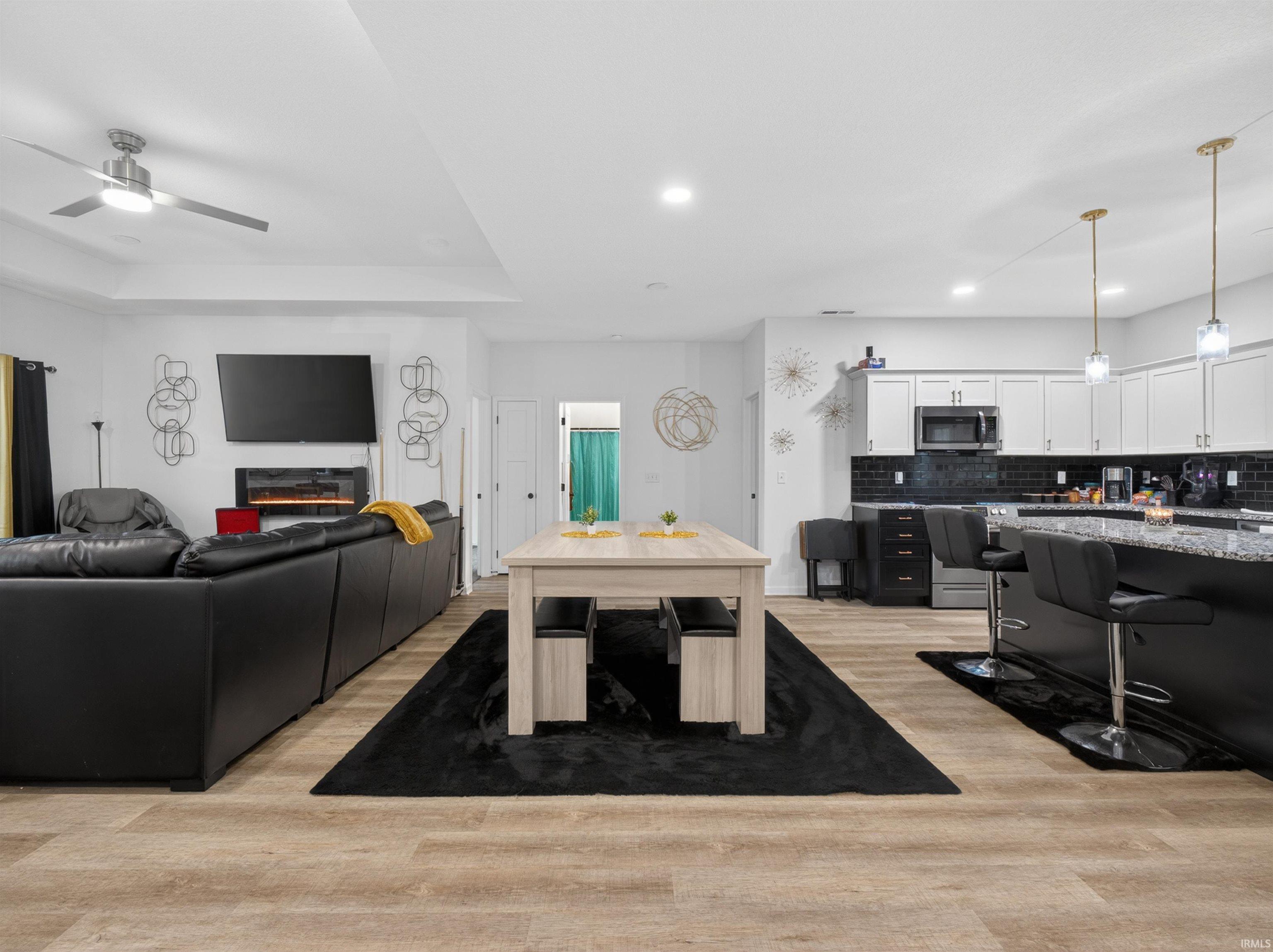 Open-concept living space featuring wood-finish flooring, a contemporary ceiling fan, and recessed lighting