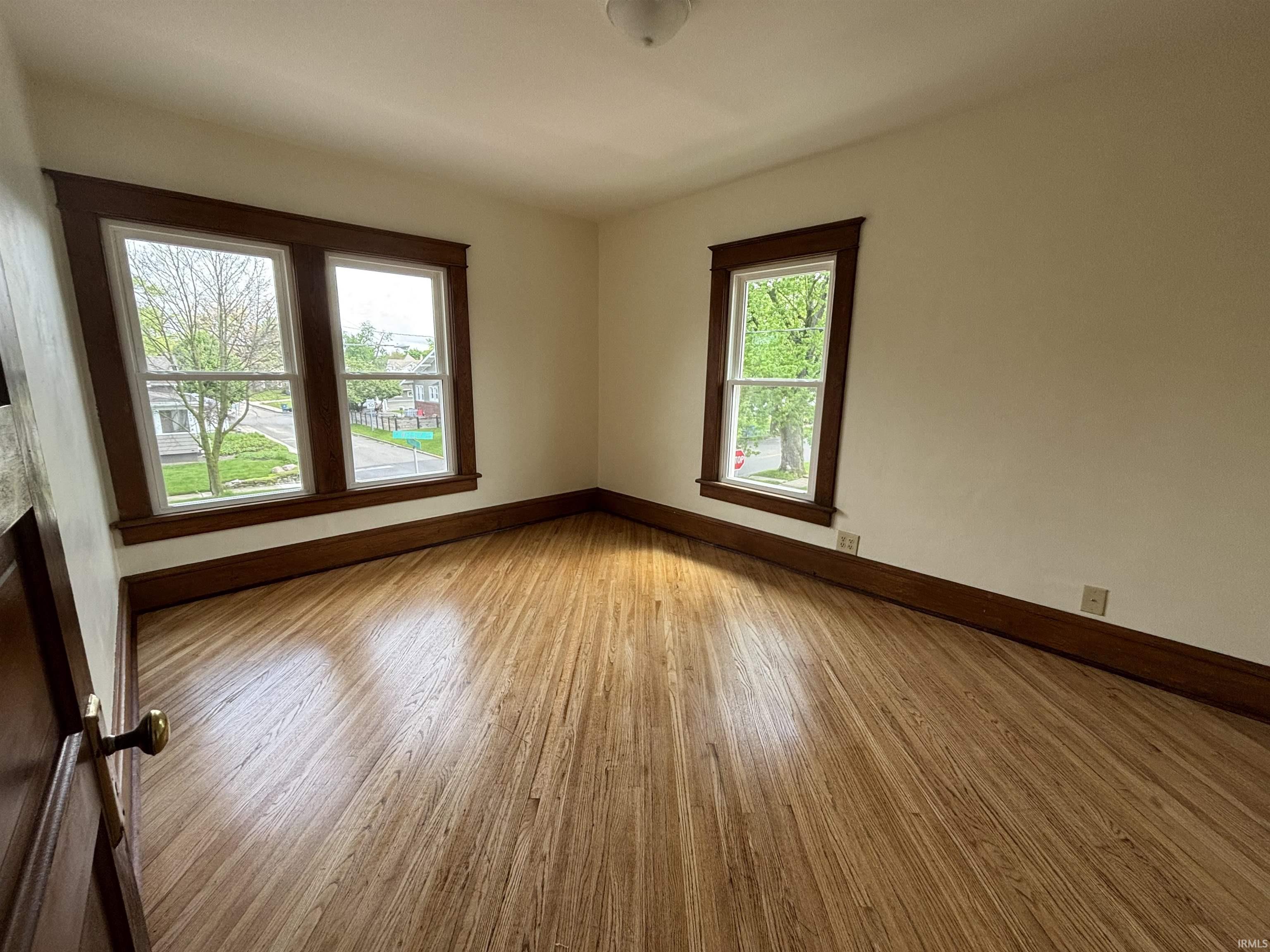 Room featuring hardwood flooring, neutral walls, and dark wood trim