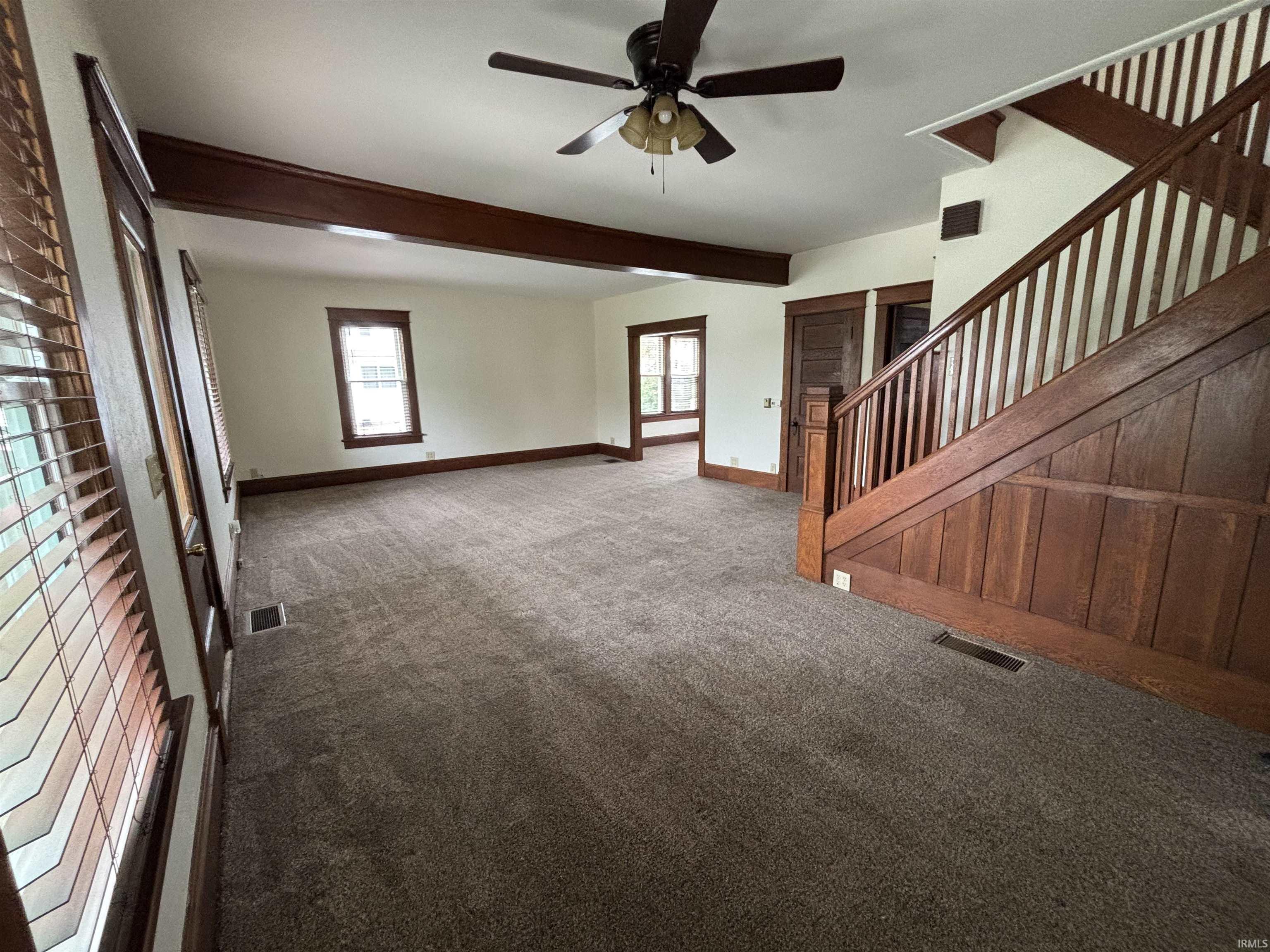 Spacious interior featuring plush carpeting and a dark wood staircase with paneling