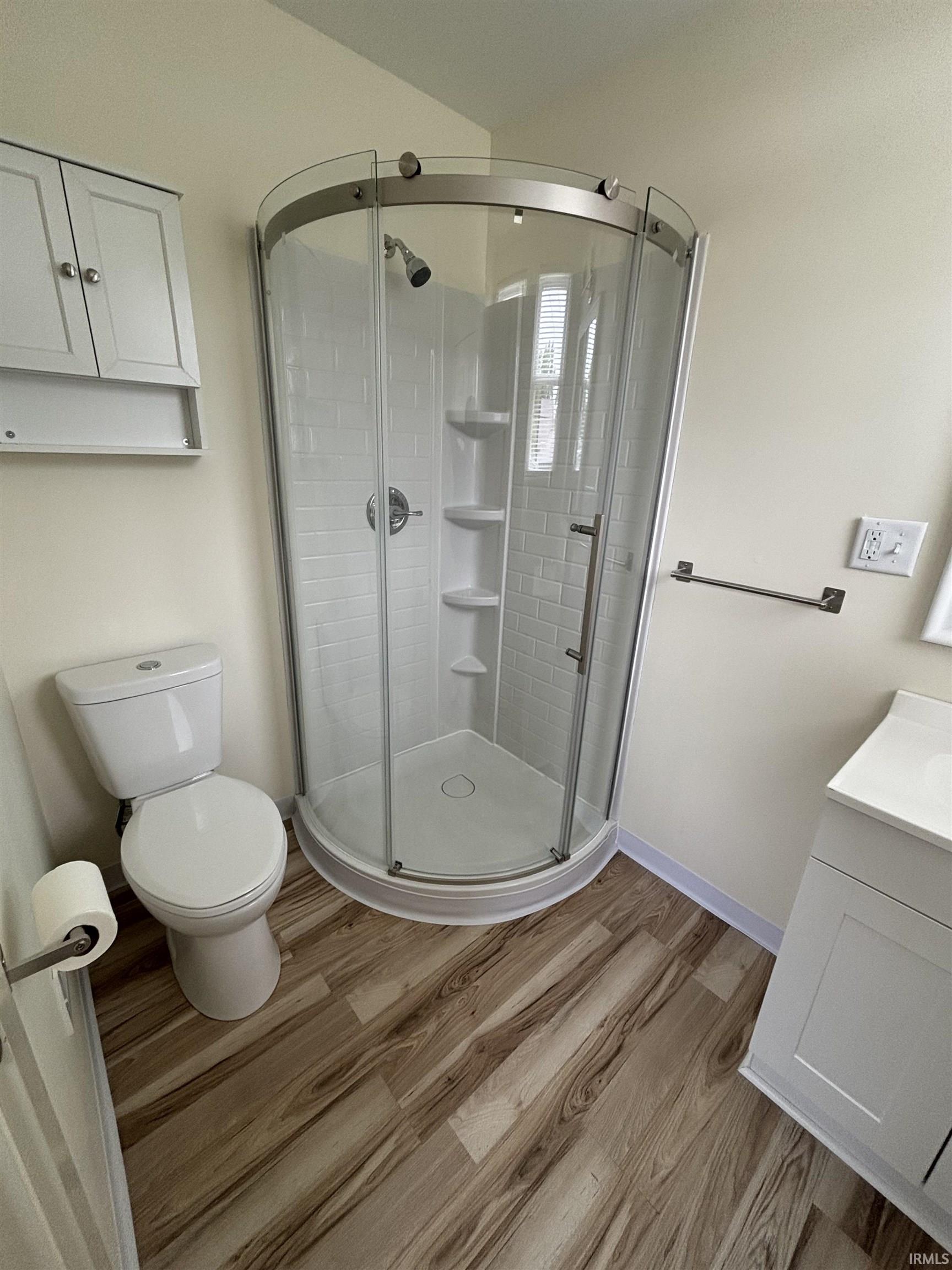 Corner shower with clear glass enclosure featuring a built-in shelf