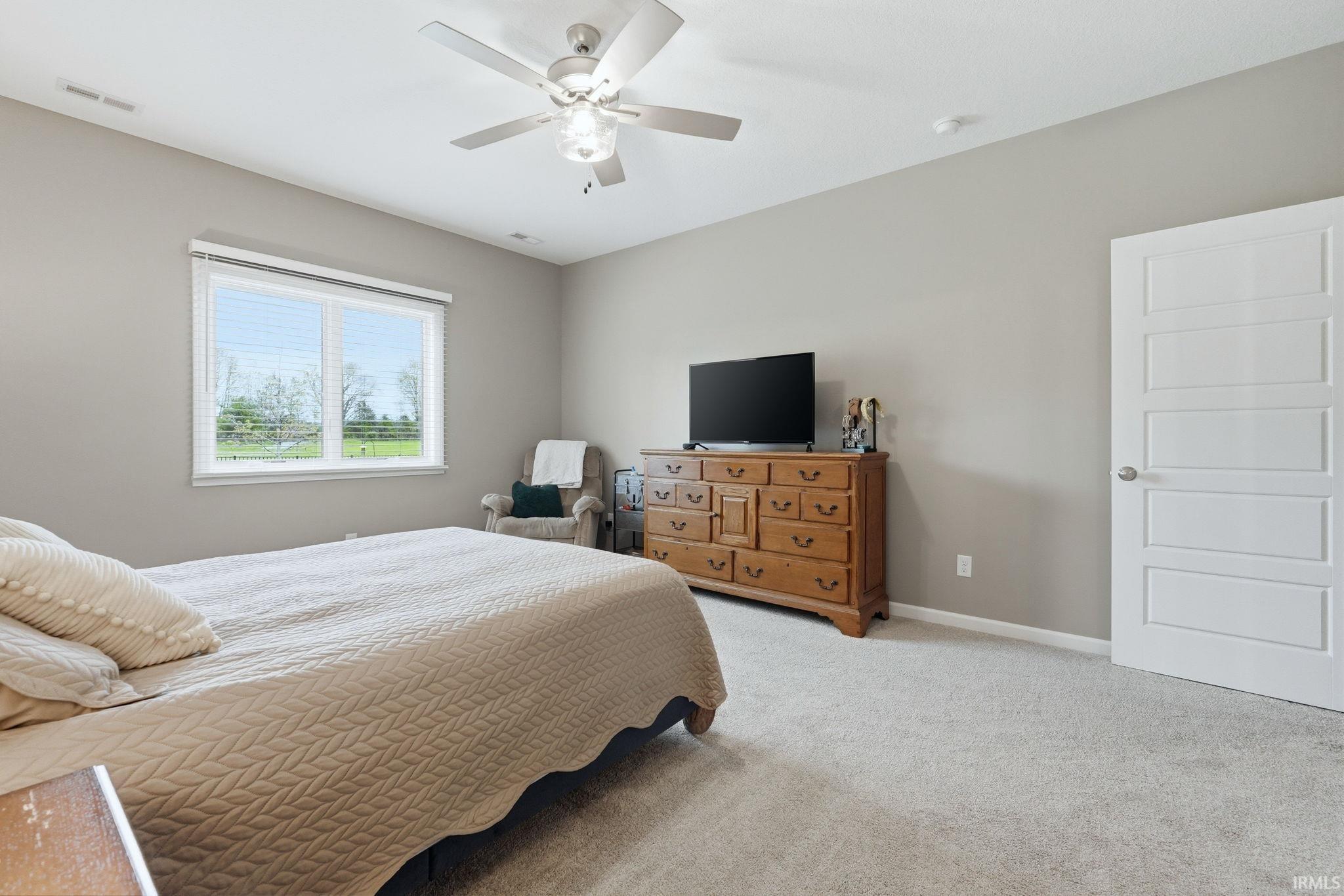 Bedroom featuring a window with blinds, light gray painted walls, and light-colored carpet flooring