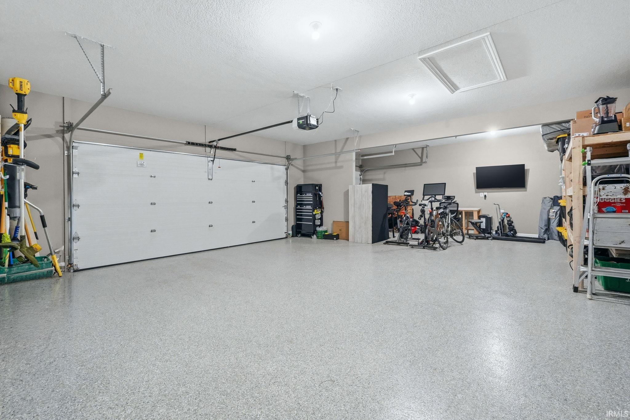 Spacious garage featuring a durable speckled epoxy floor finish, and additional storage.