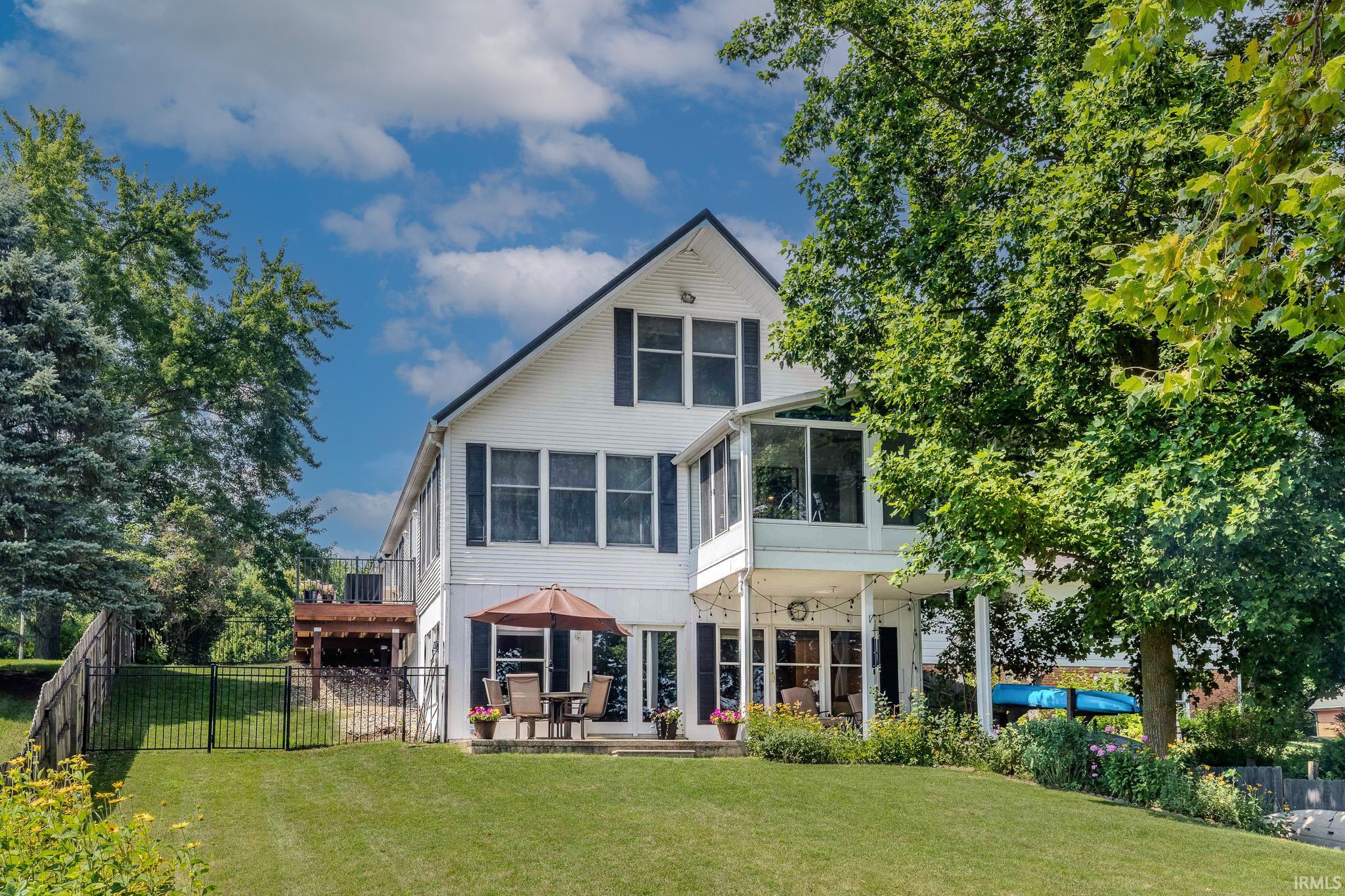 White exterior featuring black shutters, a screened-in porch, and a lower-level patio