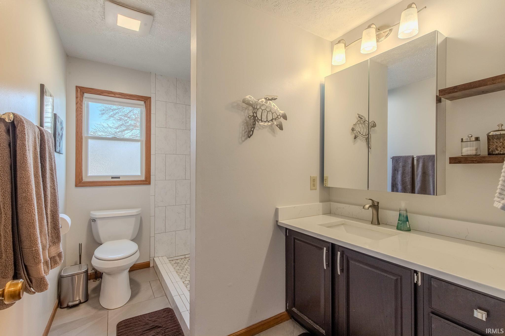 Bathroom vanity with a white countertop and dark wood-finish cabinetry