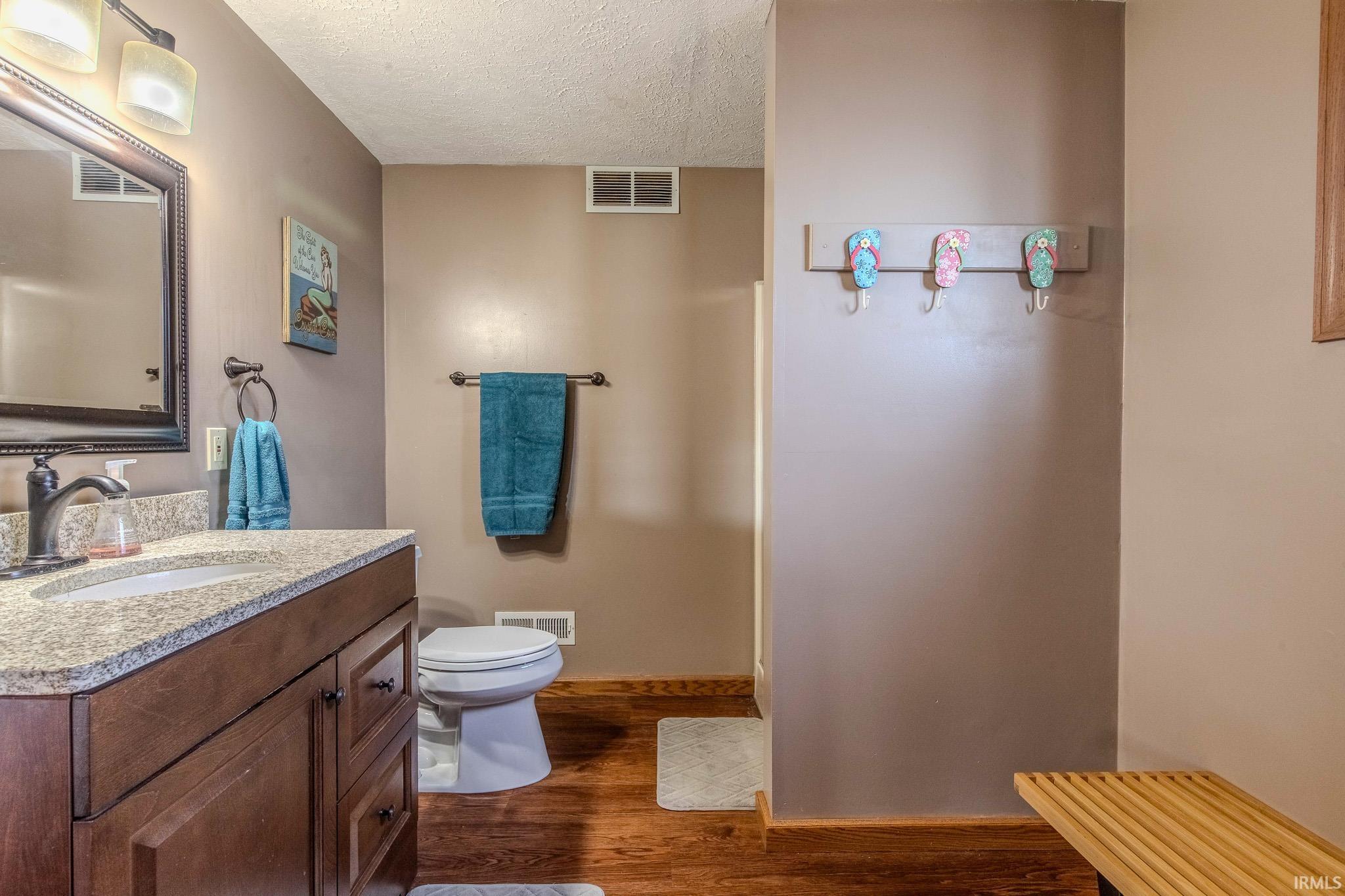 Bathroom with a single vanity featuring a speckled countertop, undermount sink, and dark wood-finish cabinetry