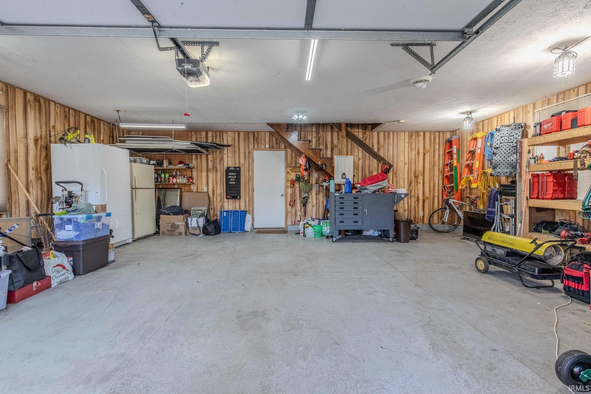 Spacious garage featuring wood-paneled walls and a concrete floor