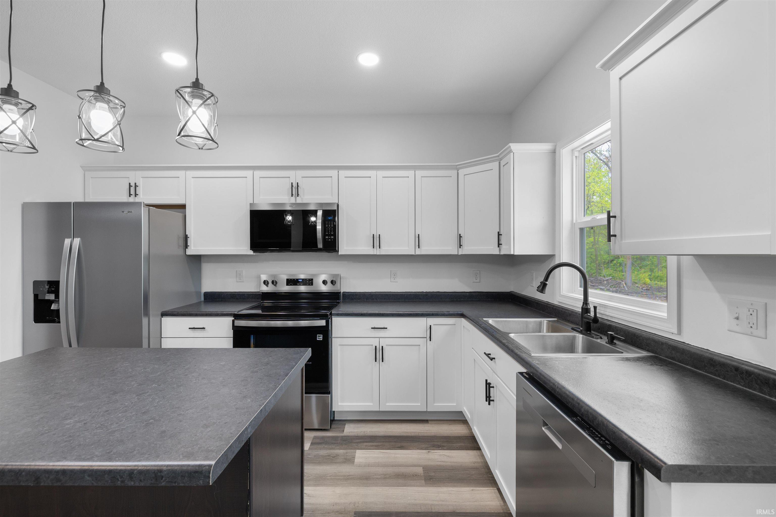 Modern kitchen featuring white cabinetry, dark countertops, and stainless steel appliances