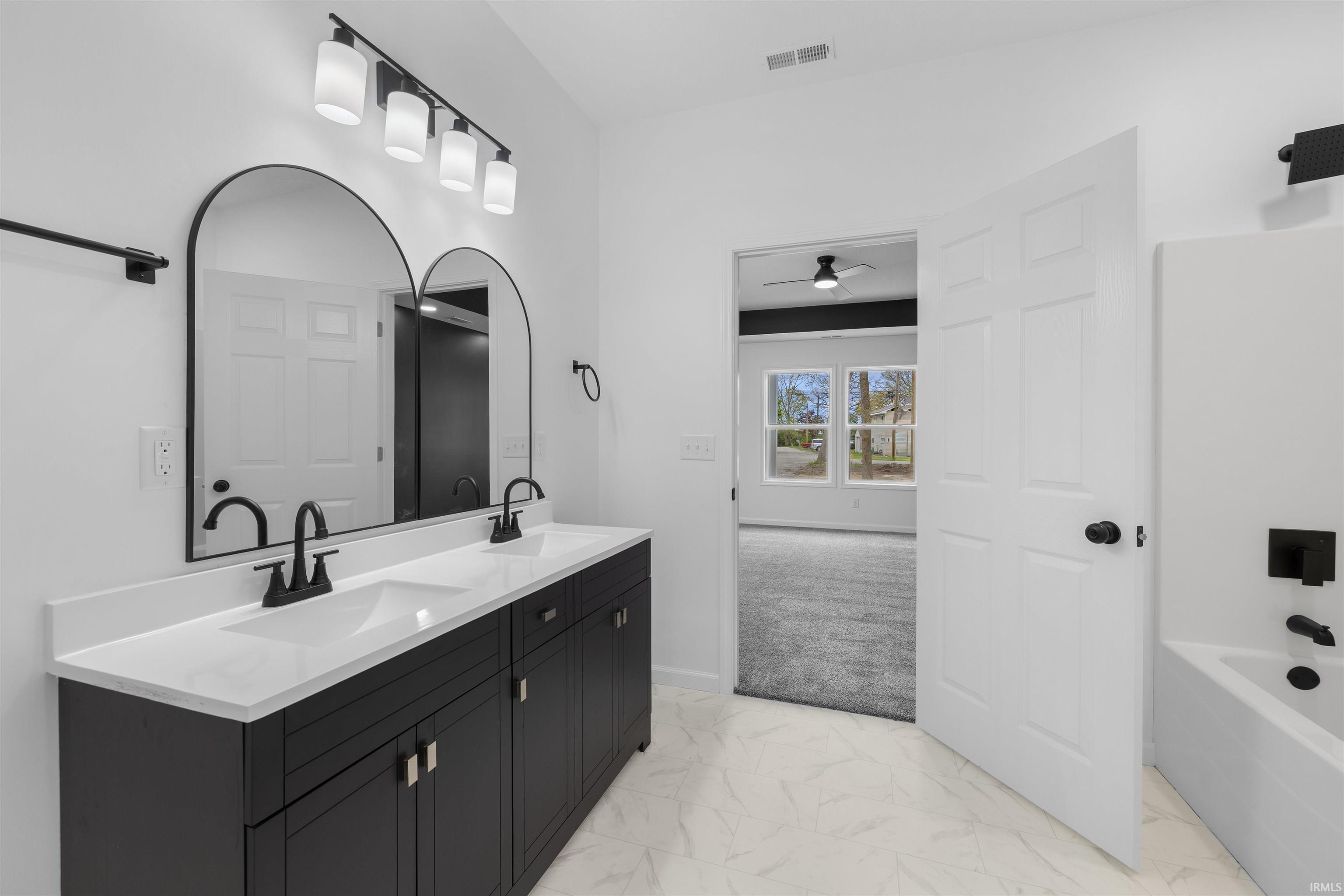 Double vanity featuring dark cabinetry, white countertops, and matte black fixtures