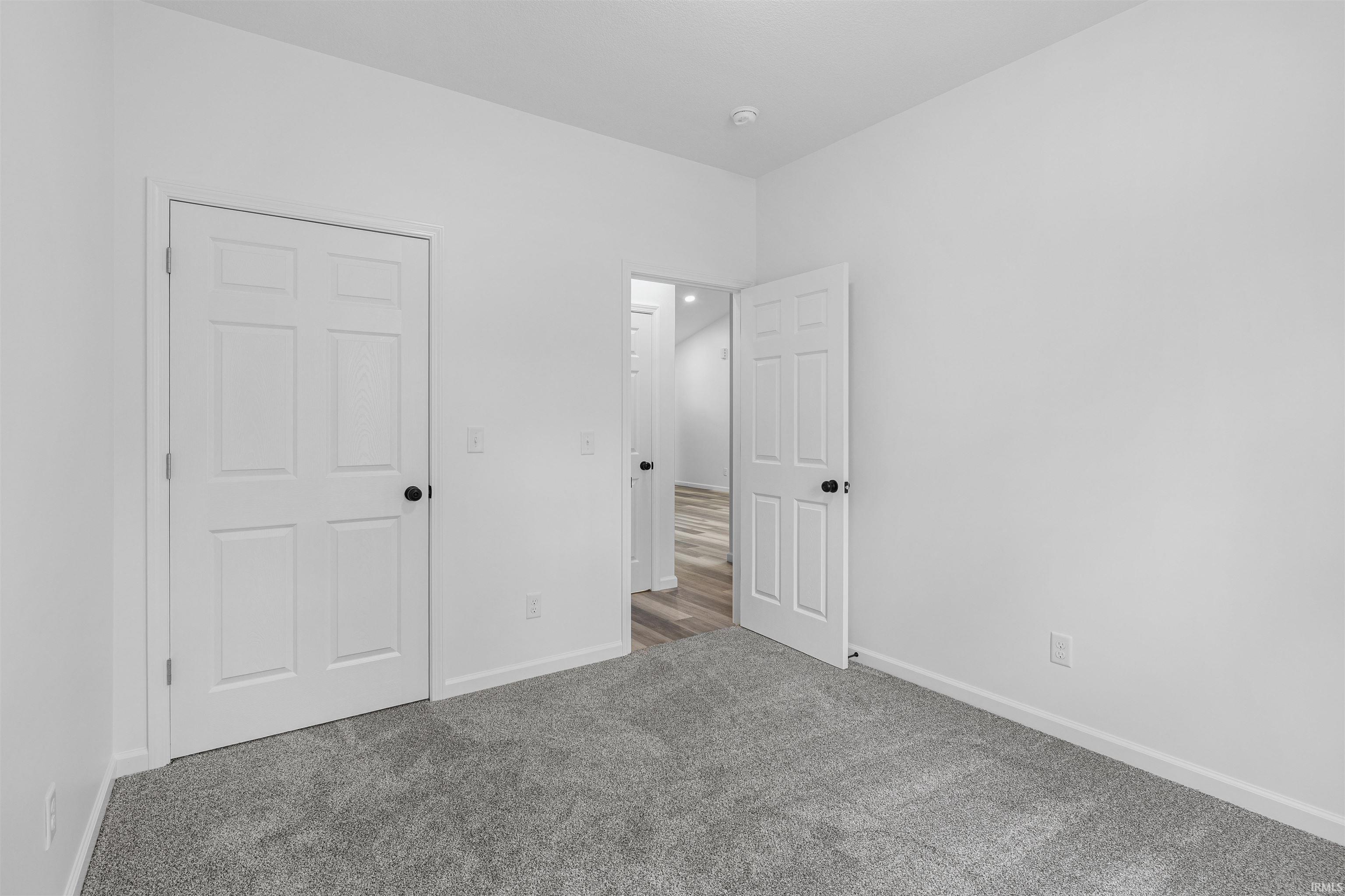 Room featuring grey carpeting, white interior walls, and contrasting black door hardware