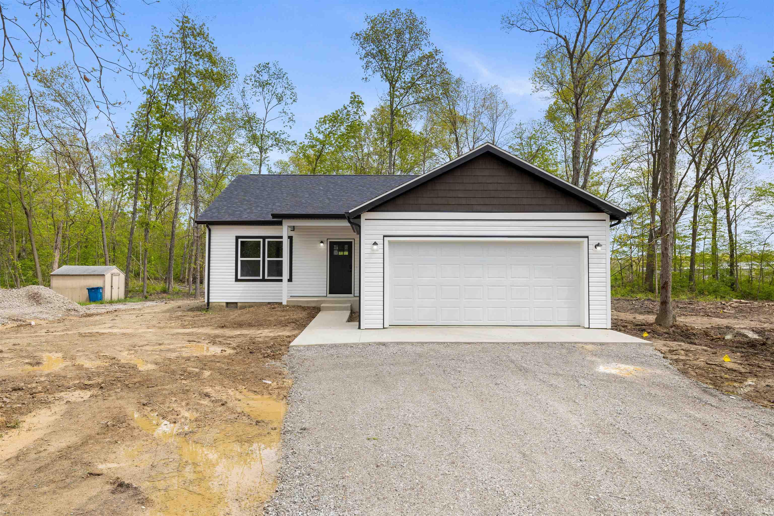 Single-story residence featuring white horizontal siding, a dark roof, and a dark brown gable accent
