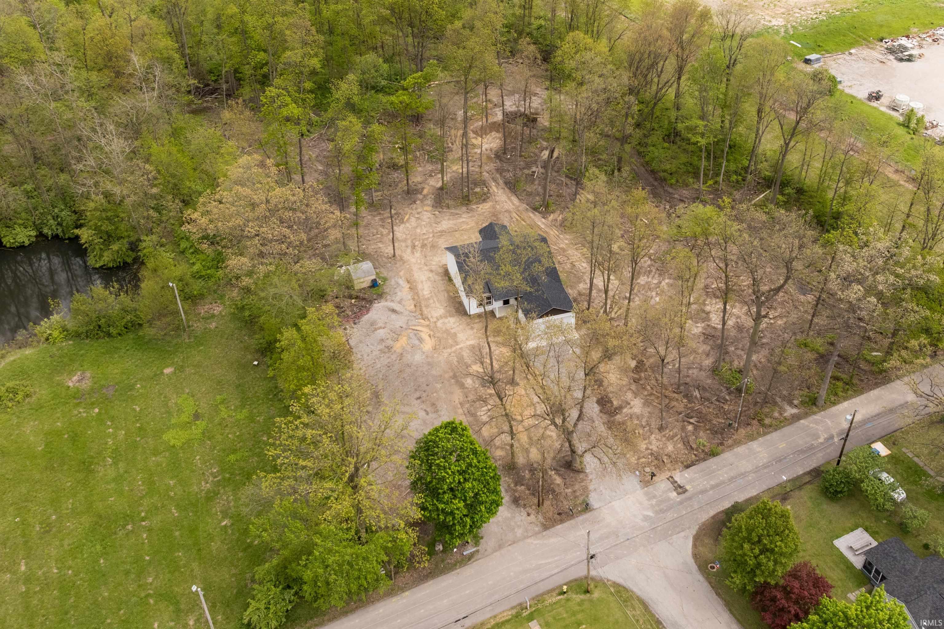 Extensive wooded parcel featuring a single-story structure with a dark roof, surrounded by mature trees