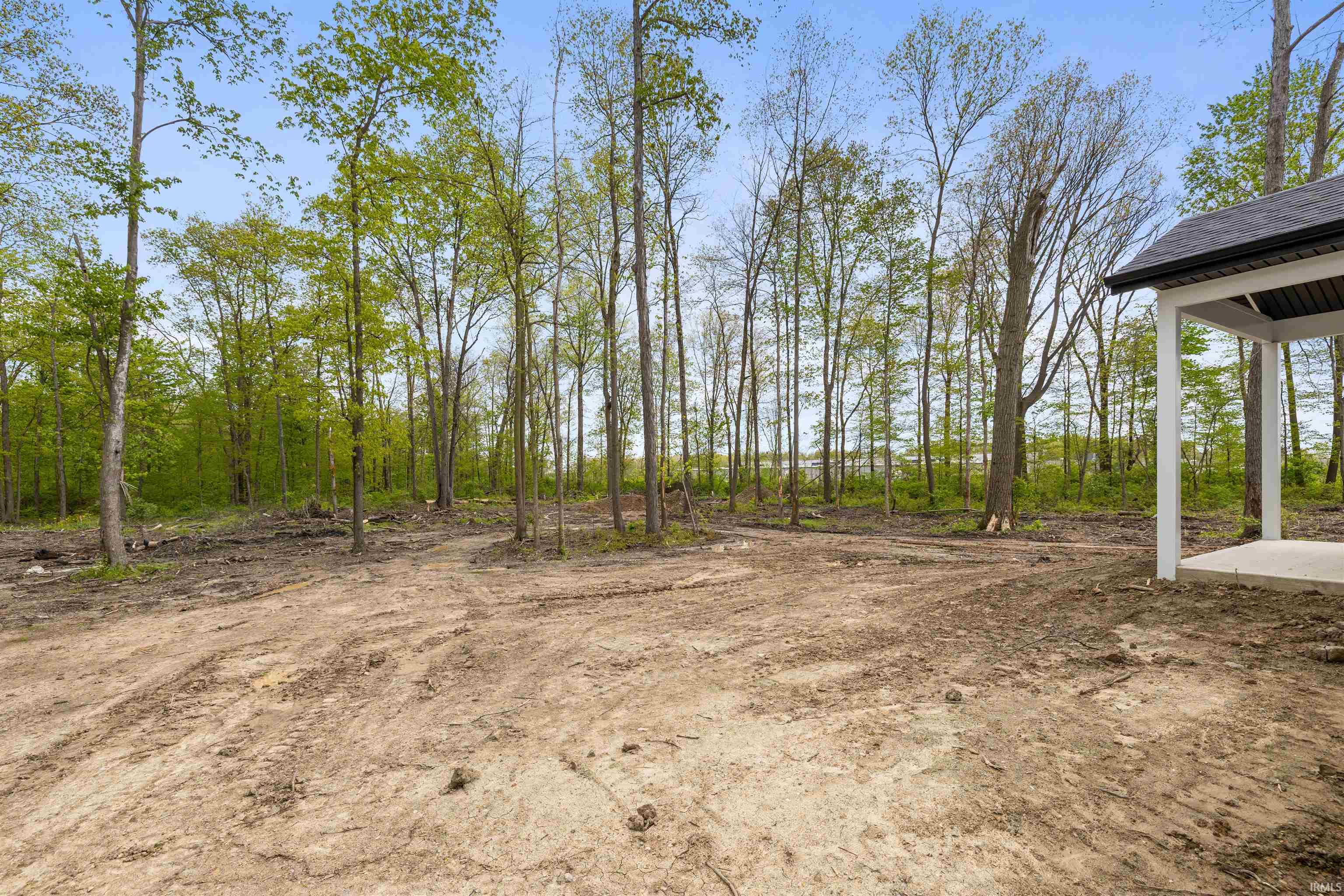 Expansive wooded lot featuring mature trees and a newly constructed covered concrete patio