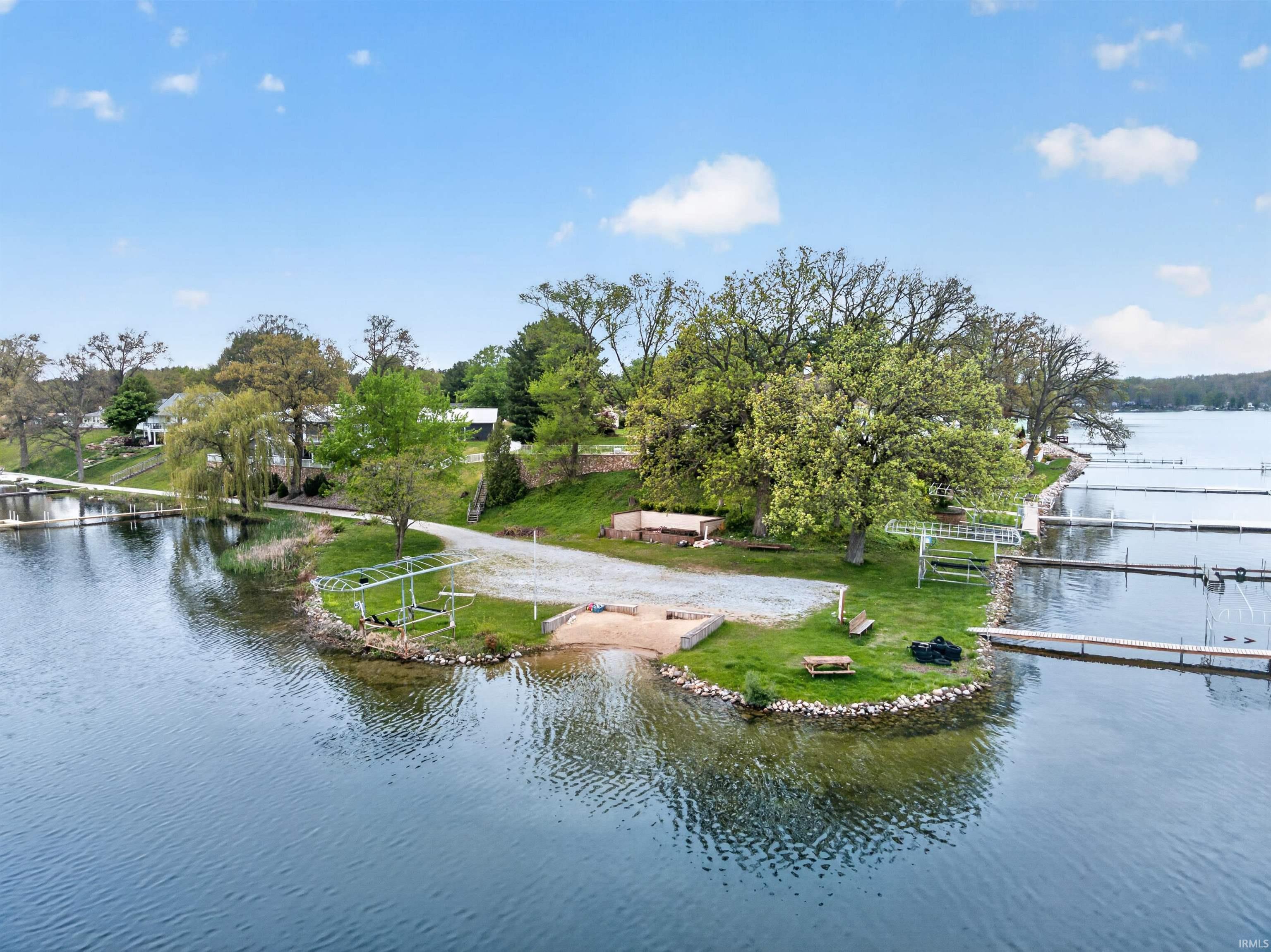 Waterfront property featuring a private boat launch, multiple boat slips, and a gravel access road