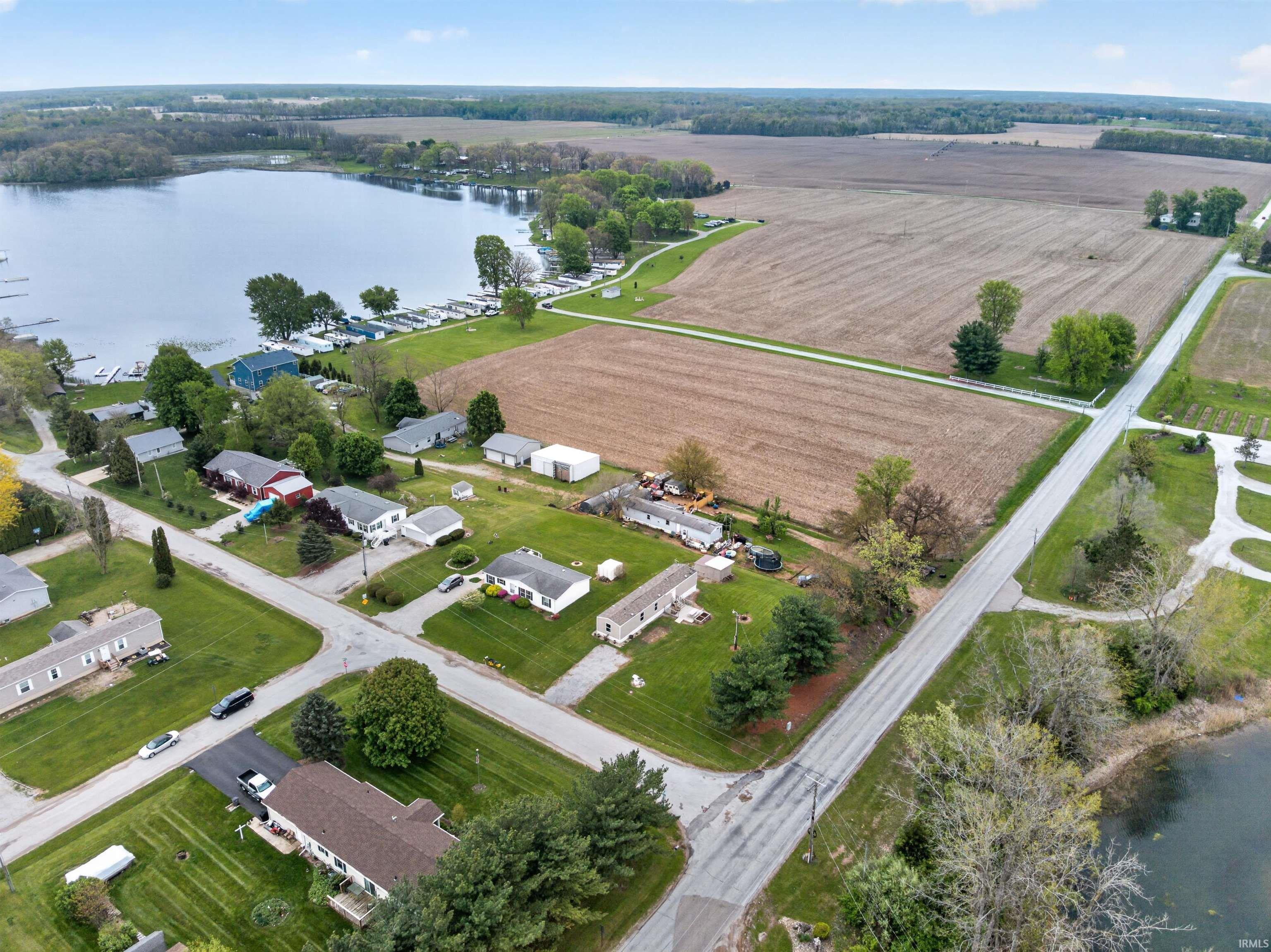 Expansive aerial capturing a freshwater lake with multiple docks, surrounding residential properties, agricultural fields, and paved roads