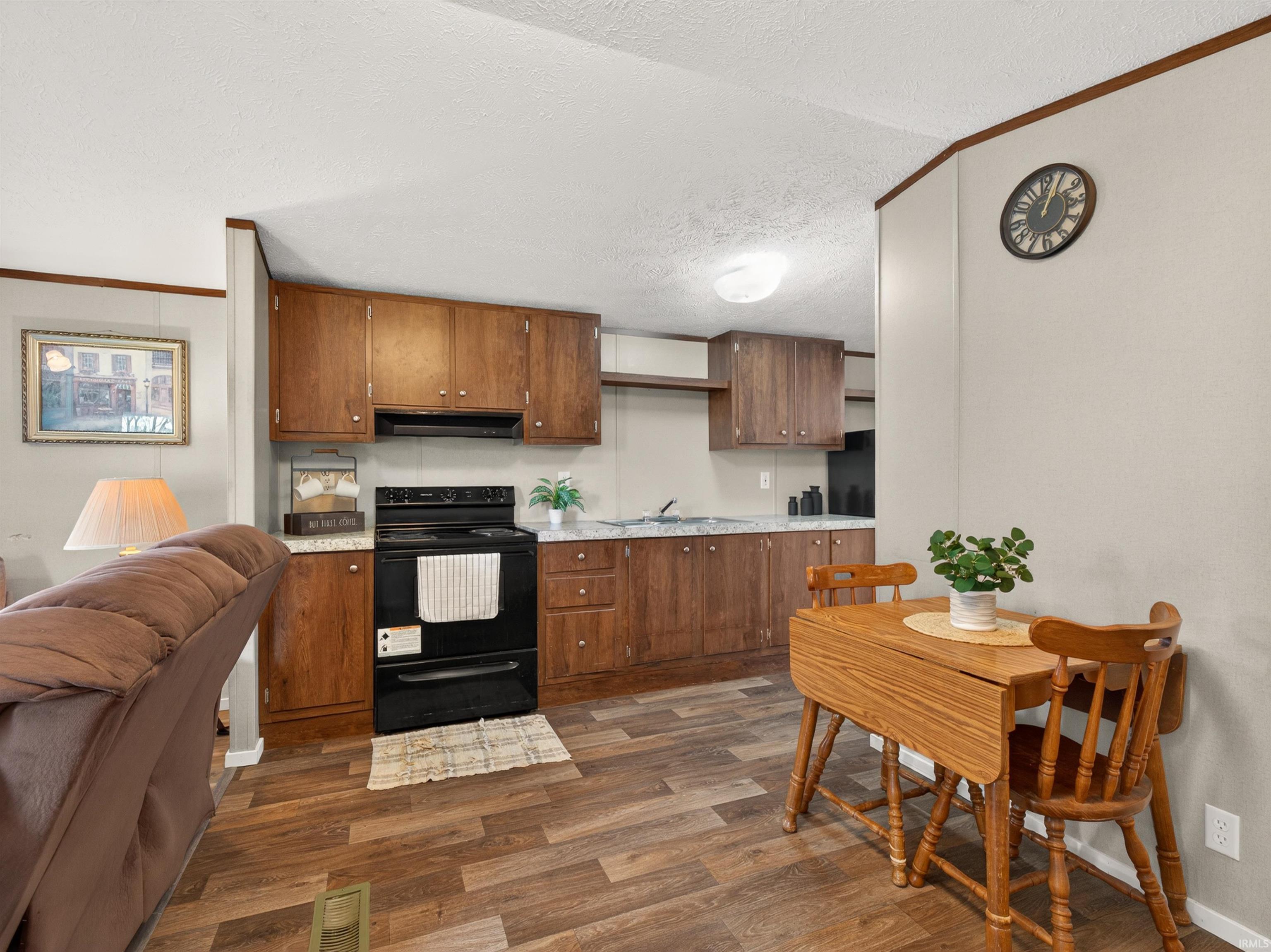 Full kitchen with wood-finish flooring, ample cabinetry, black appliances, and light-toned countertops