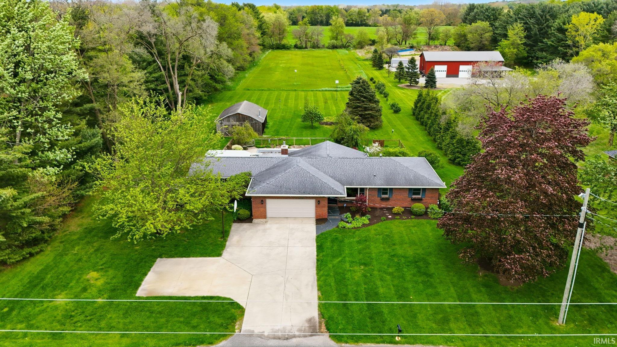 Brick ranch home featuring a dark shingle roof and a concrete driveway