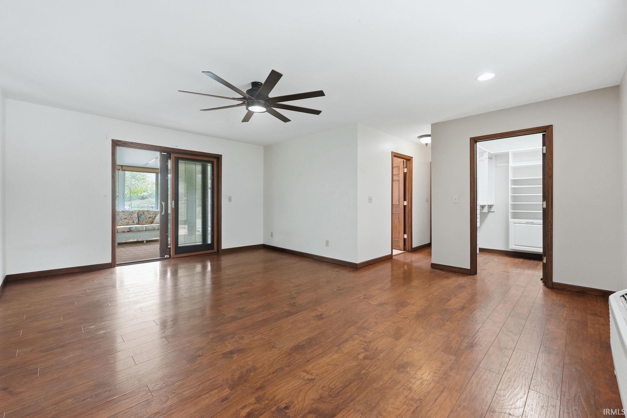 Spacious room featuring wood-finish flooring, white walls, and dark wood trim