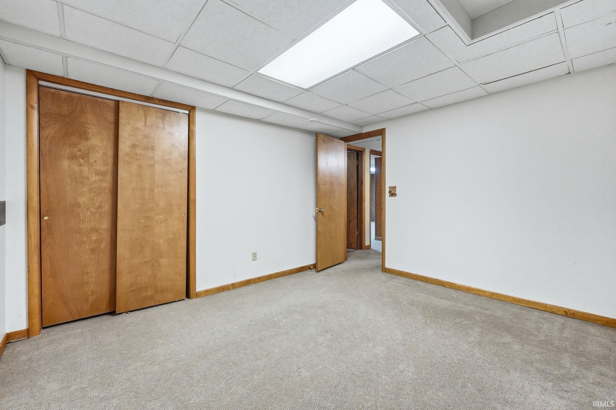 Carpeted room with white walls and a drop ceiling