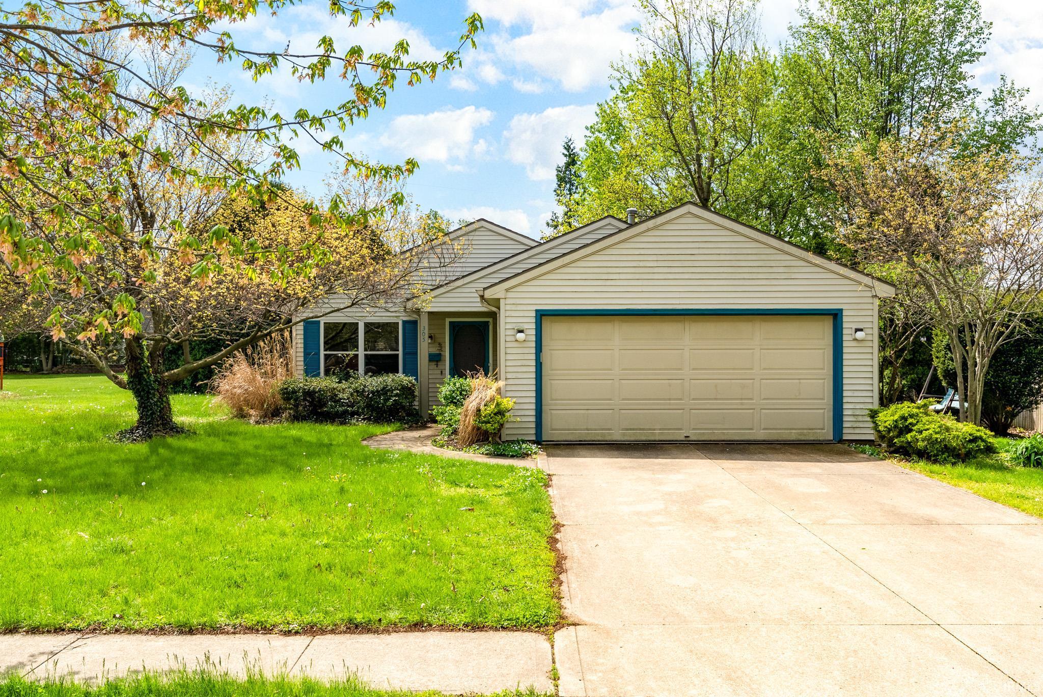 Single-story residence featuring light-colored siding, a prominent two-car garage, and a concrete driveway