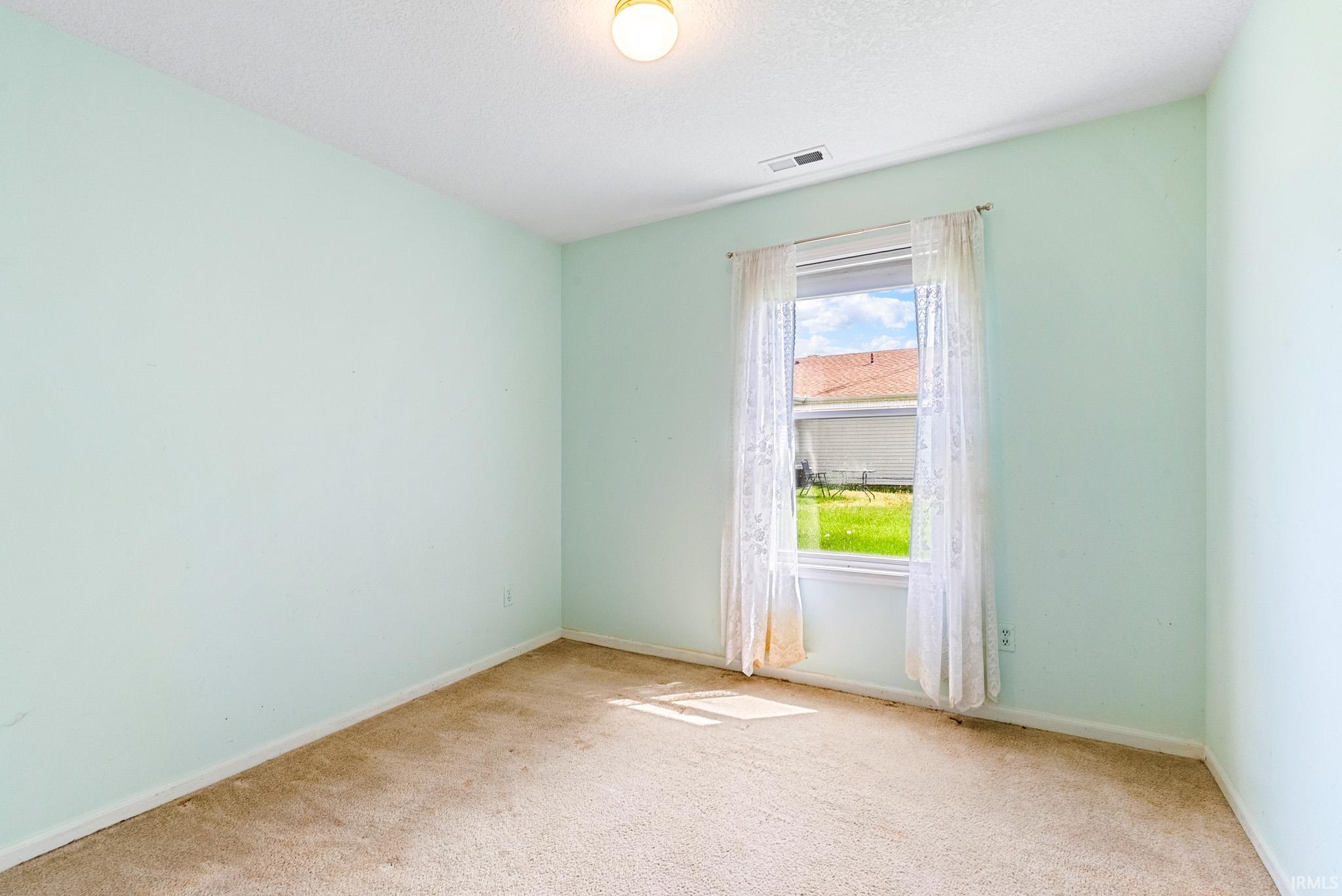 Carpeted room featuring light blue walls, a single window, and an overhead light fixture