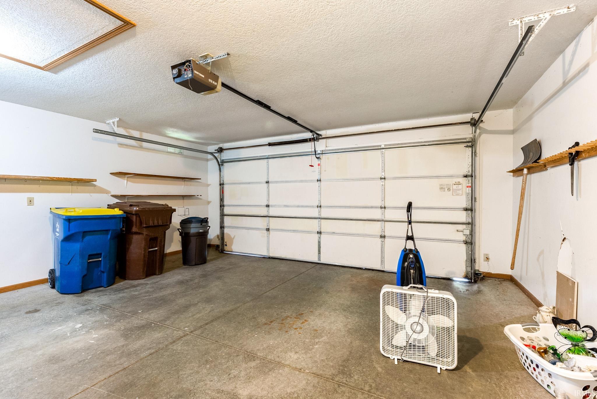 Spacious garage featuring a concrete floor, overhead lighting, and white walls