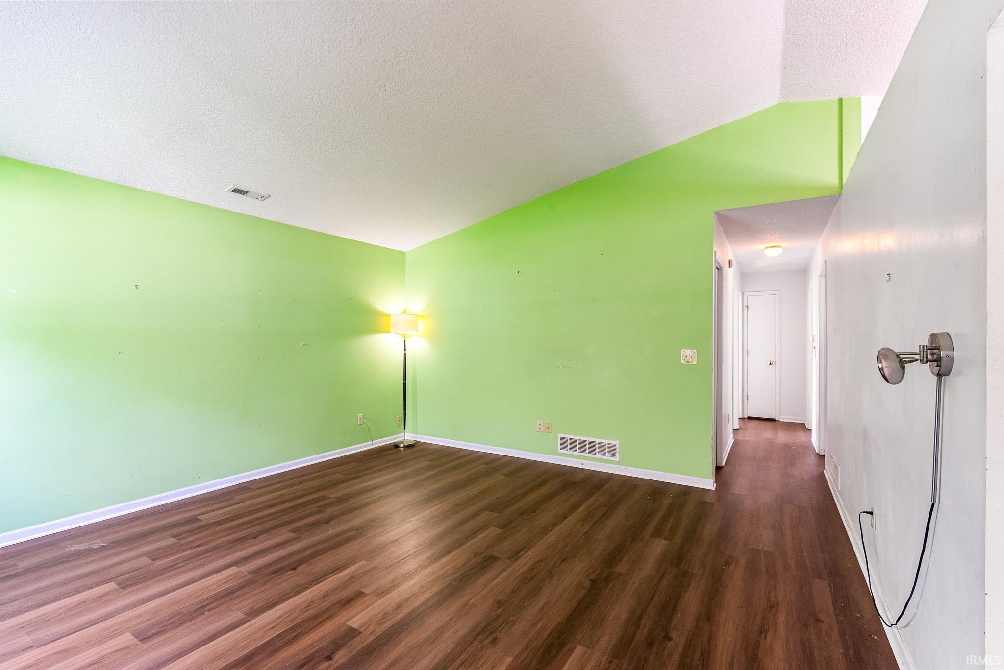 Open interior space featuring wood-finish flooring, white baseboards, and a bright green accent wall