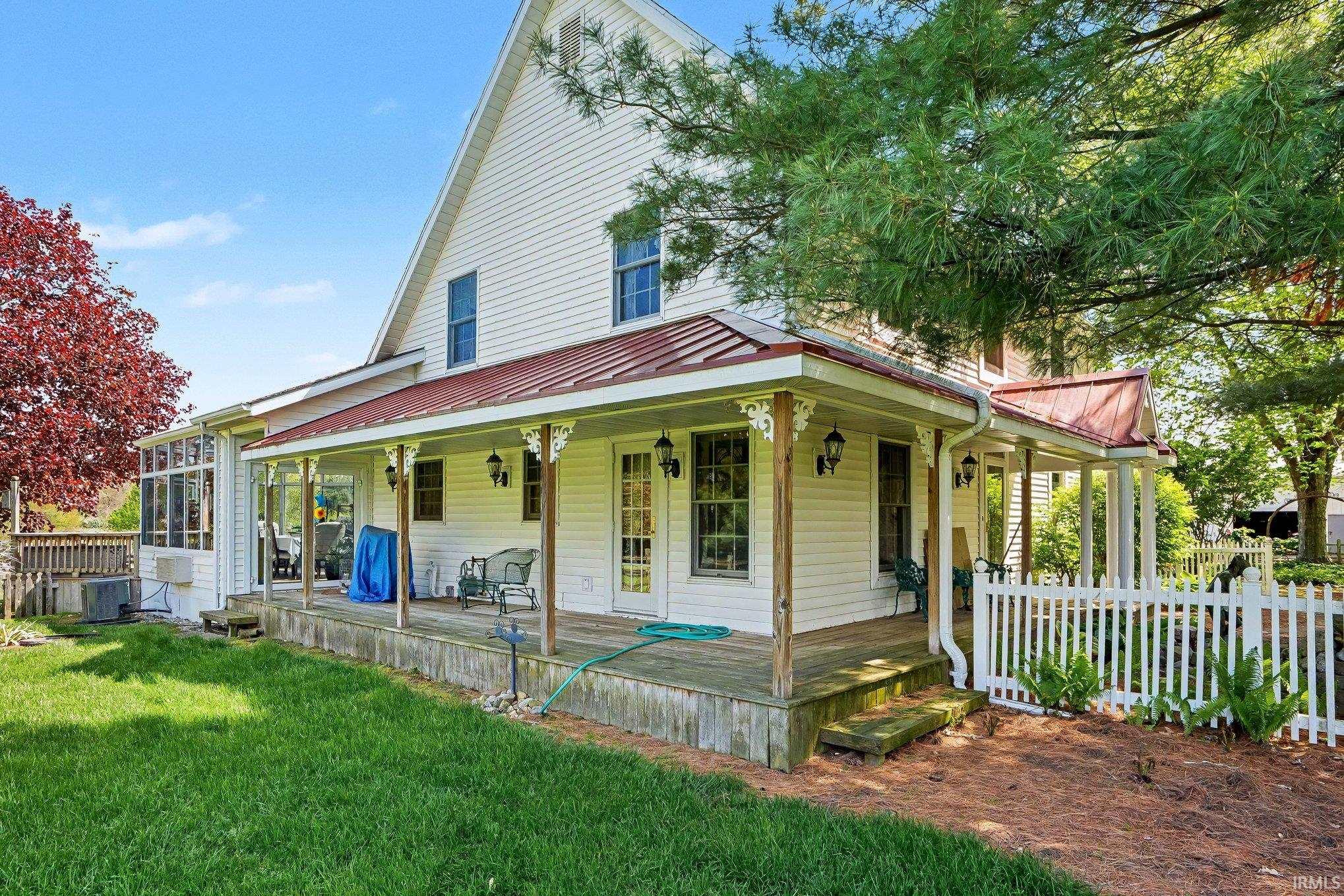White siding exterior with a red metal roof and a full-length covered porch