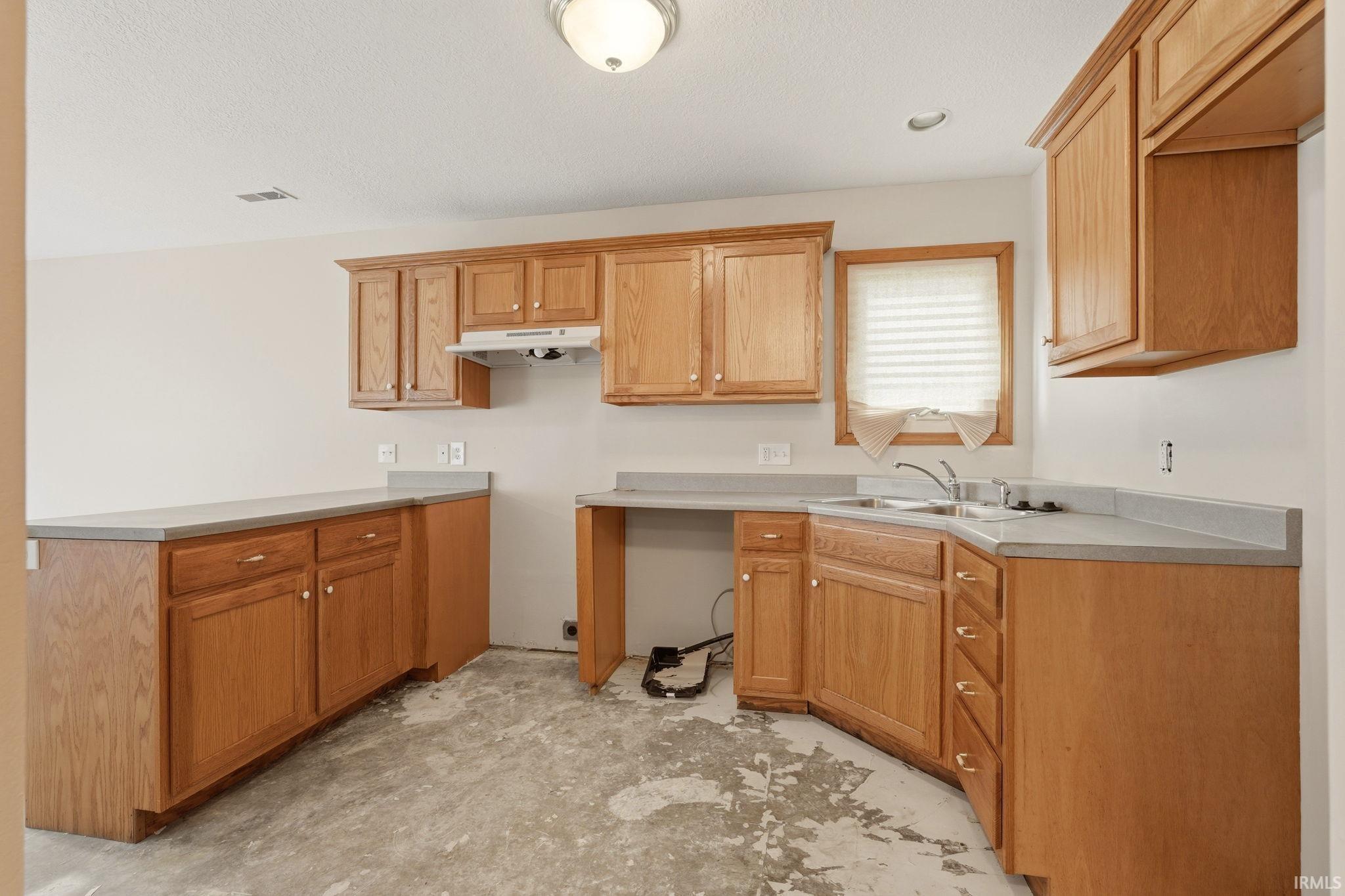 Kitchen featuring light wood cabinetry, gray countertops, and a double basin stainless steel sink