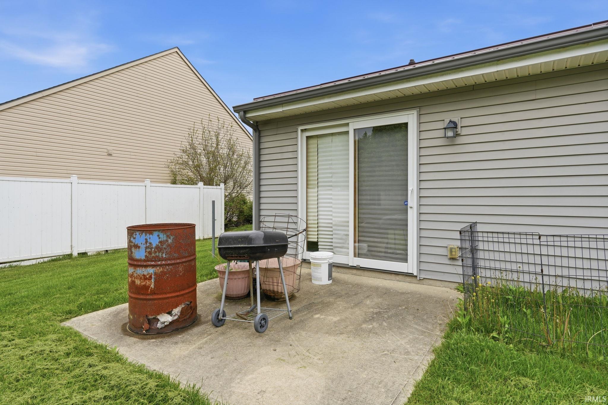 Concrete patio with sliding glass door access, exterior wall lighting, and horizontal vinyl siding