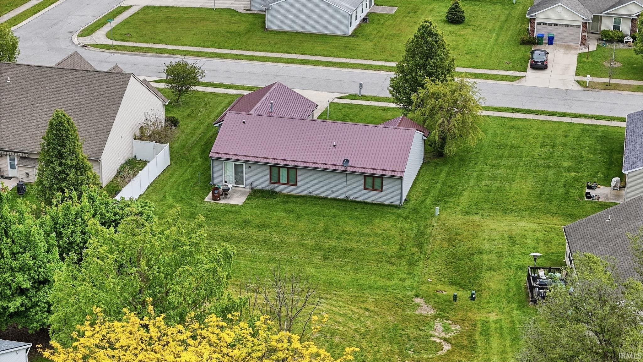 Single-story residence featuring a maroon metal roof, light gray siding, and a rear patio