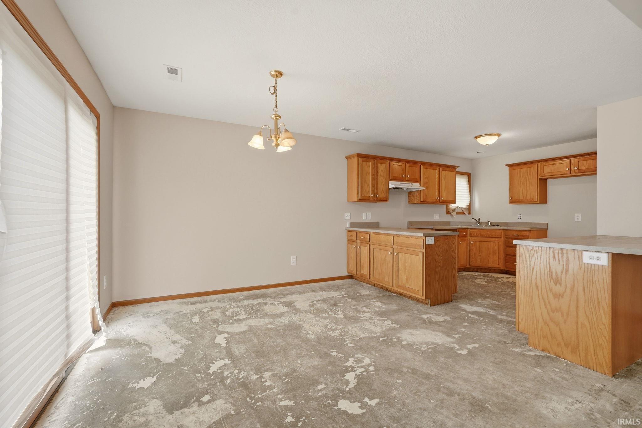 Kitchen and dining area featuring light-toned cabinetry, light countertops, and a full-size sliding glass door with blinds