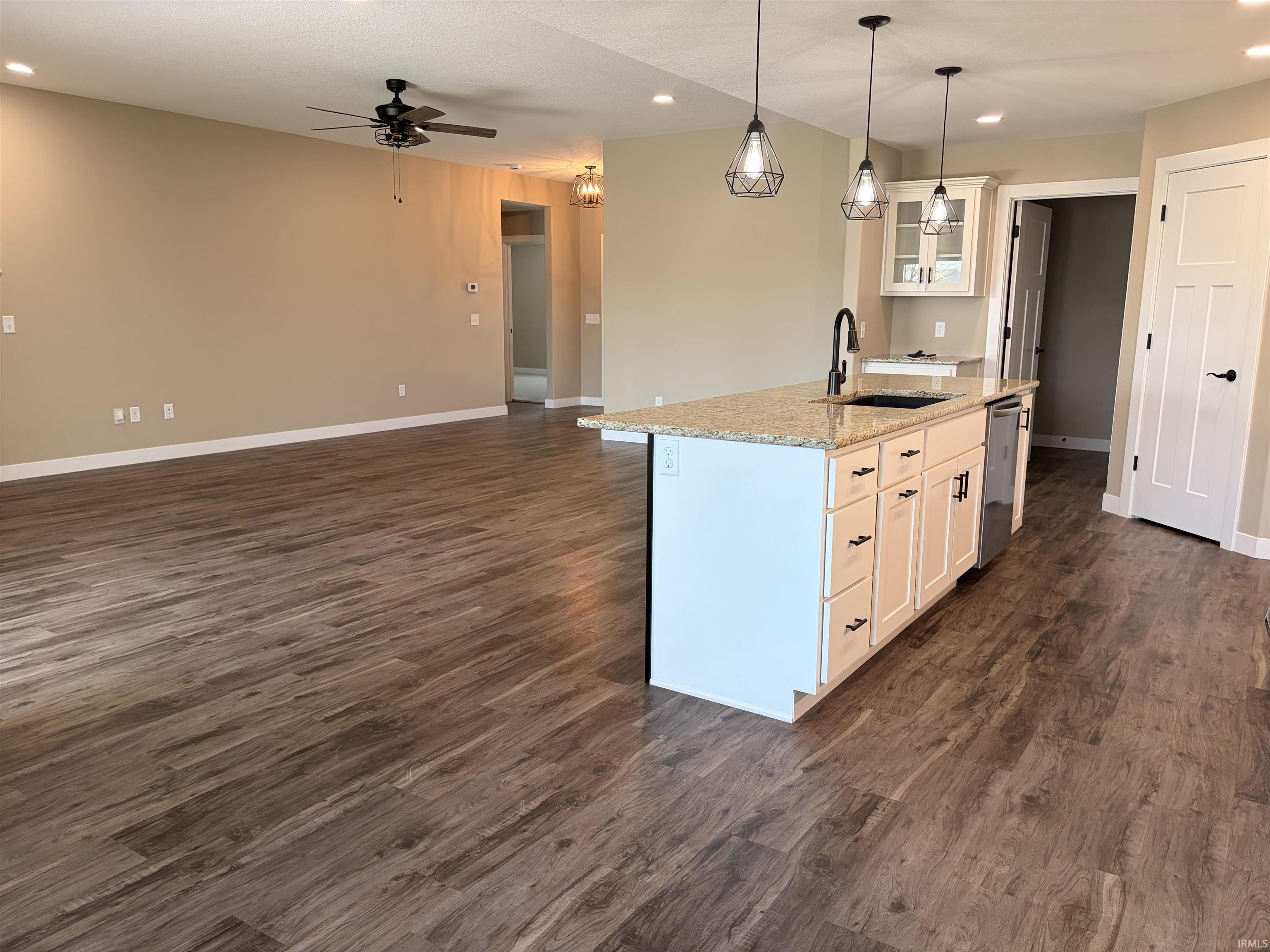 Kitchen island featuring a dual-basin sink, black gooseneck faucet, light granite countertop, and white cabinetry with black hardware